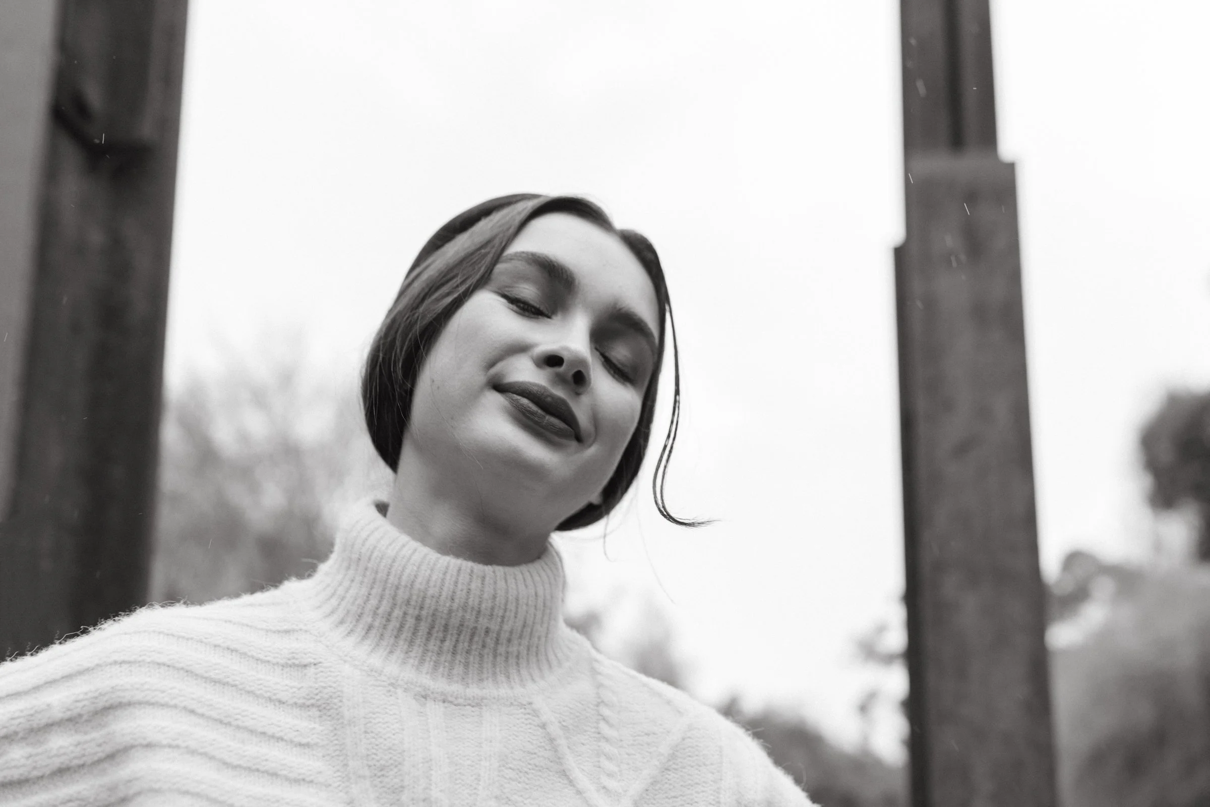 Model smiles with woollen vest on in the rain.