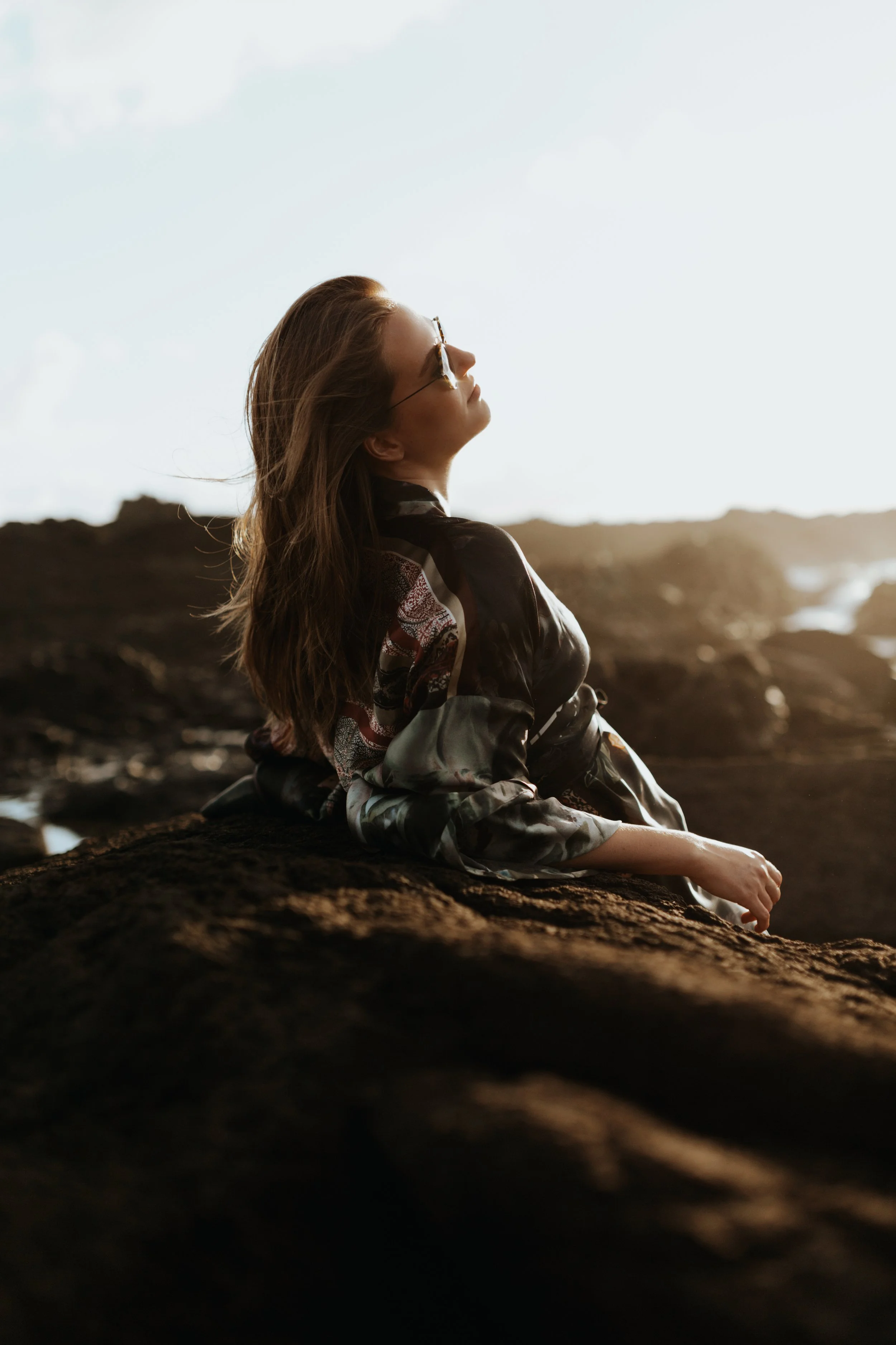 Model basks in sun at beach in silk kimono.