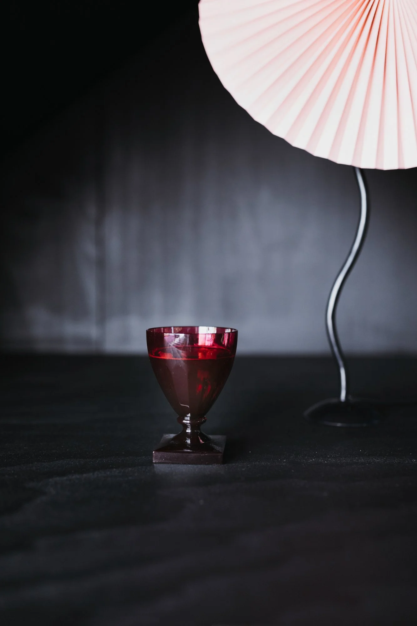 Red goblet on black table in commercial product photo.