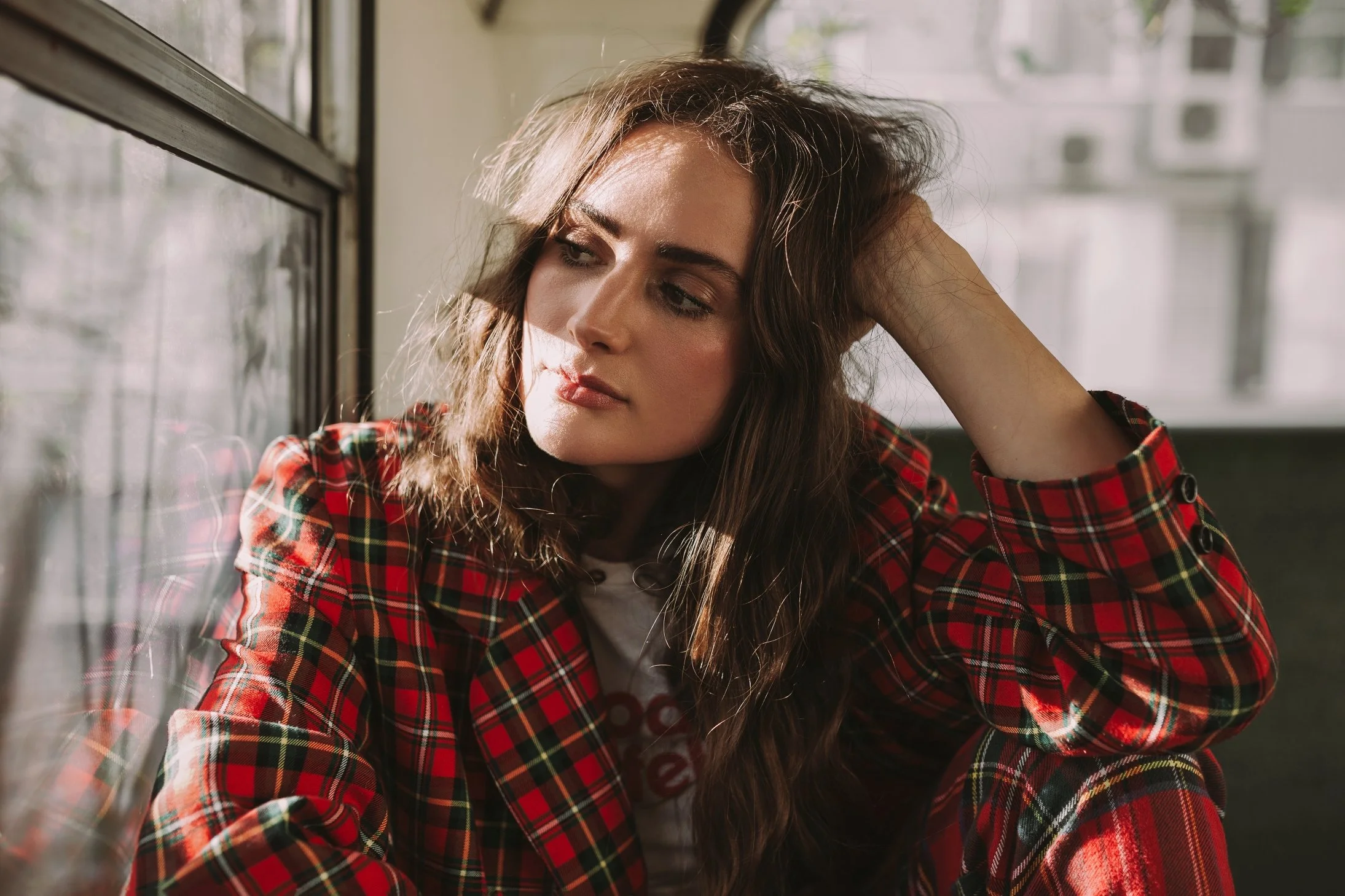 Musician sits in bus wearing red plaid suit for profile photo shoot.
