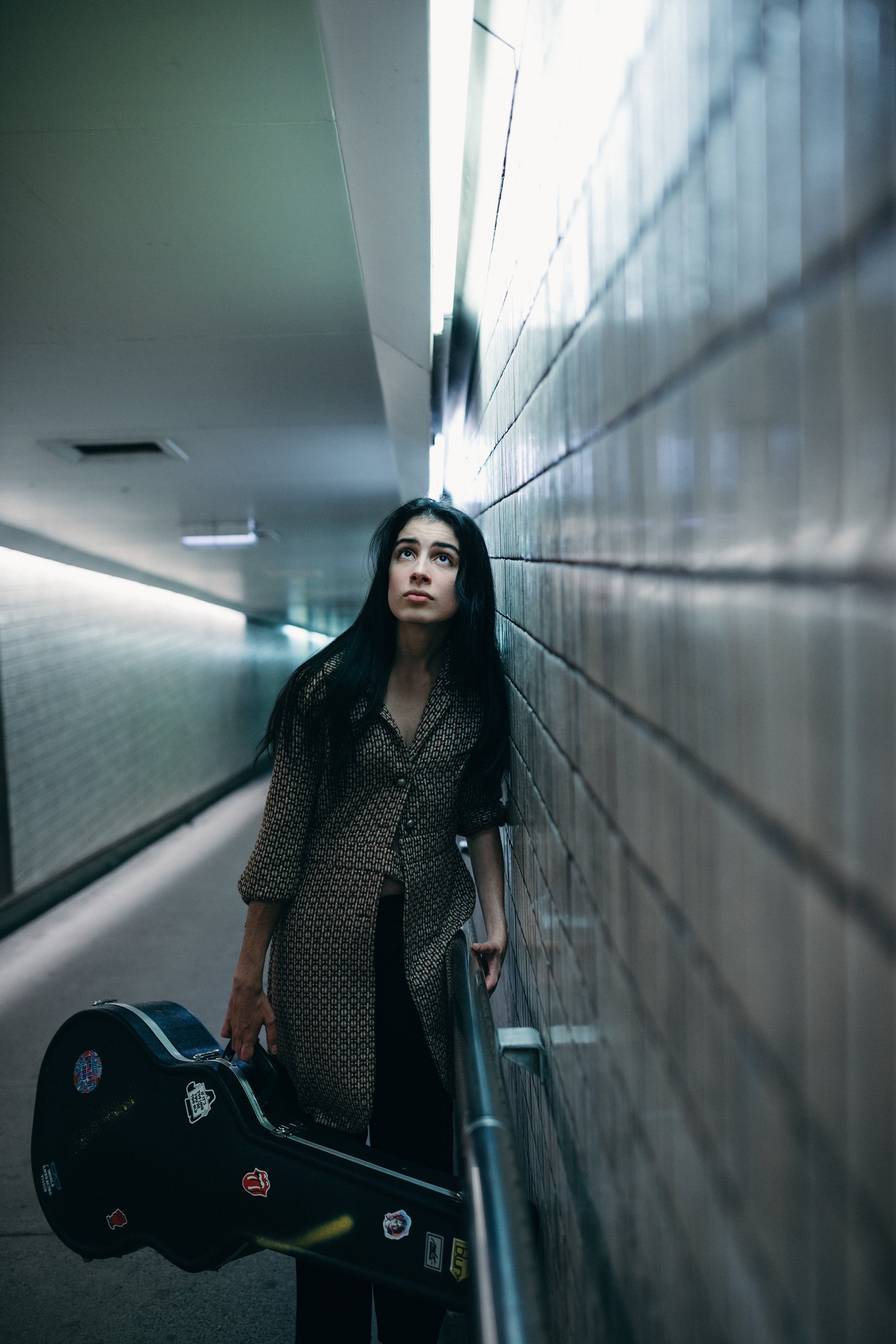 Musician named "Felony" poses in subway with guitar.