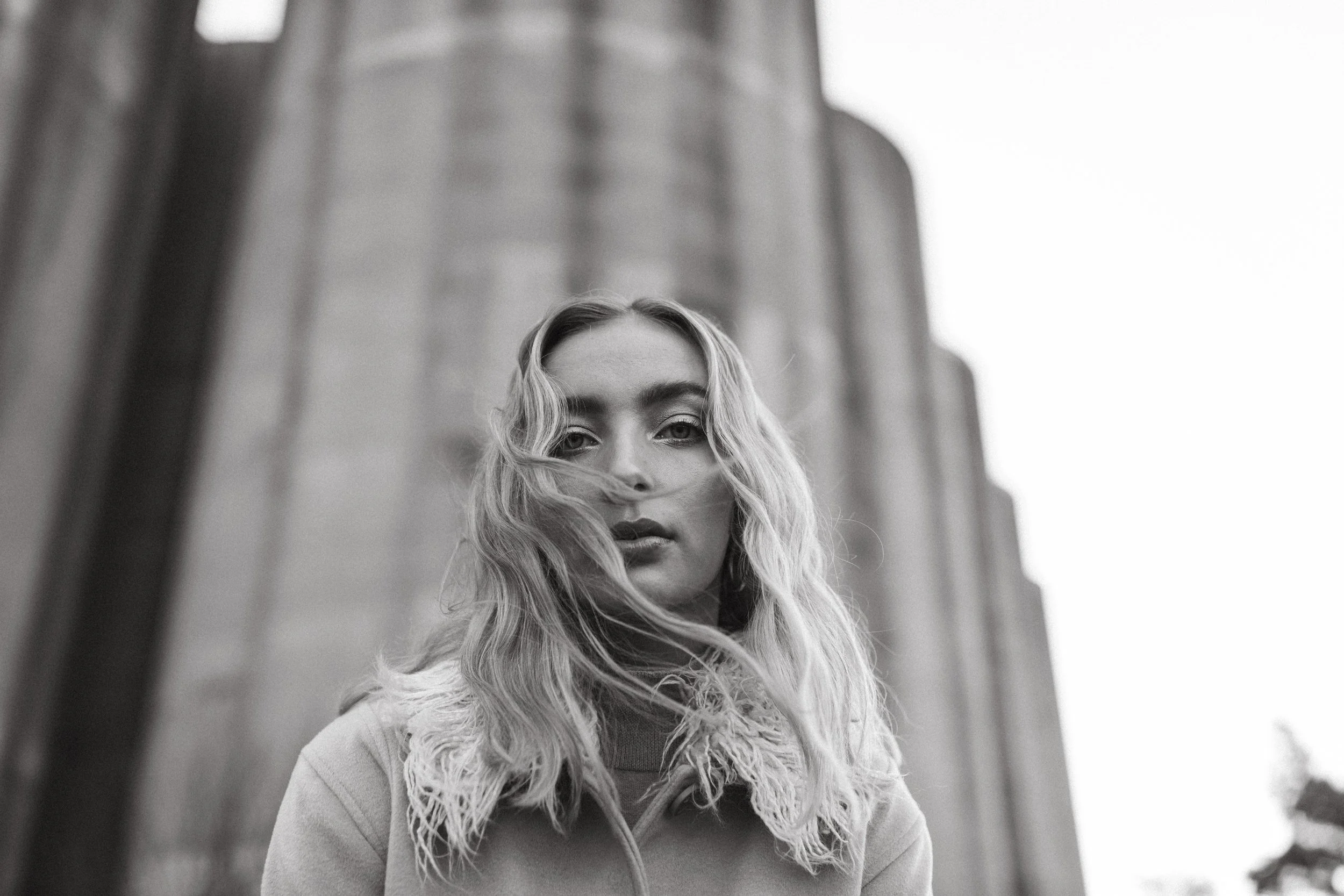 Blonde woman stands in front of silos for styled photo shoot in Hobart, Tasmania.