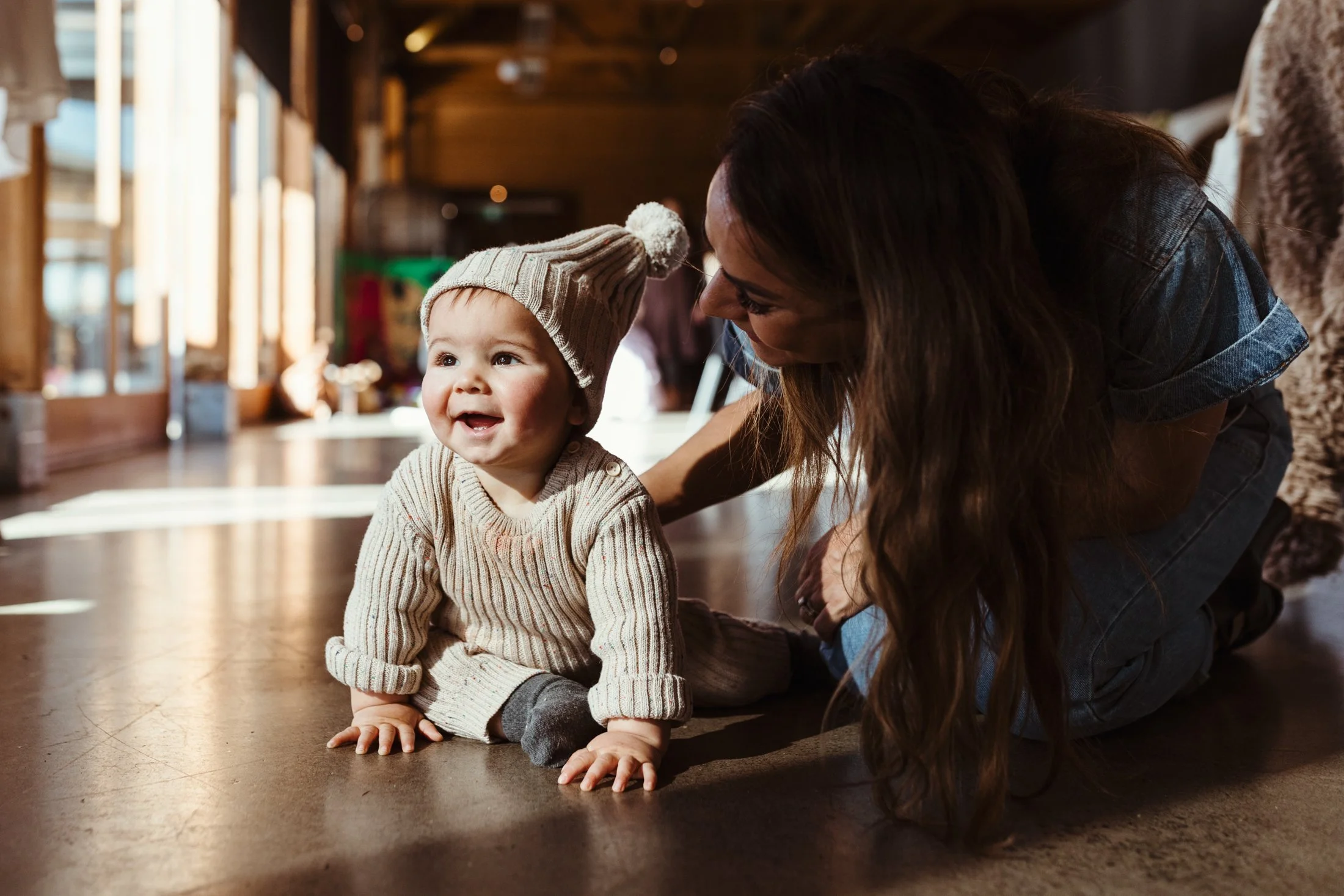 Mother and baby interact on floor at launch event.