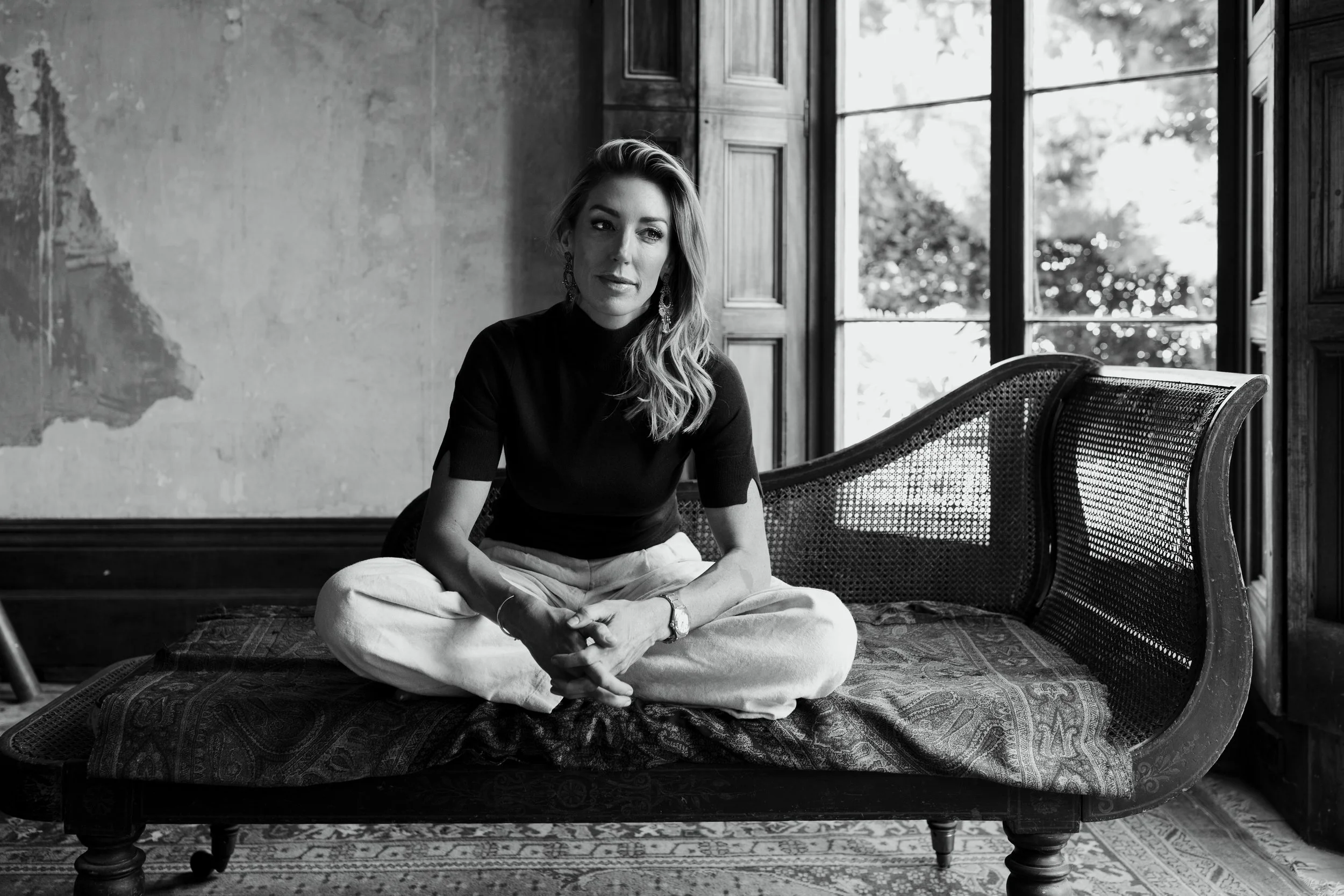 Woman sits on antique chair looking relaxed for a personal branding photo shoot.