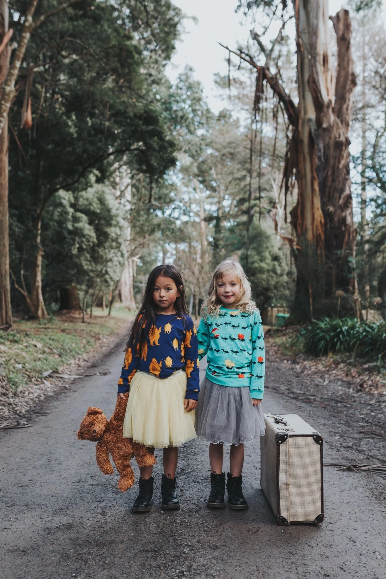 Two girls stand next to each other in country side for fashion photo shoot.