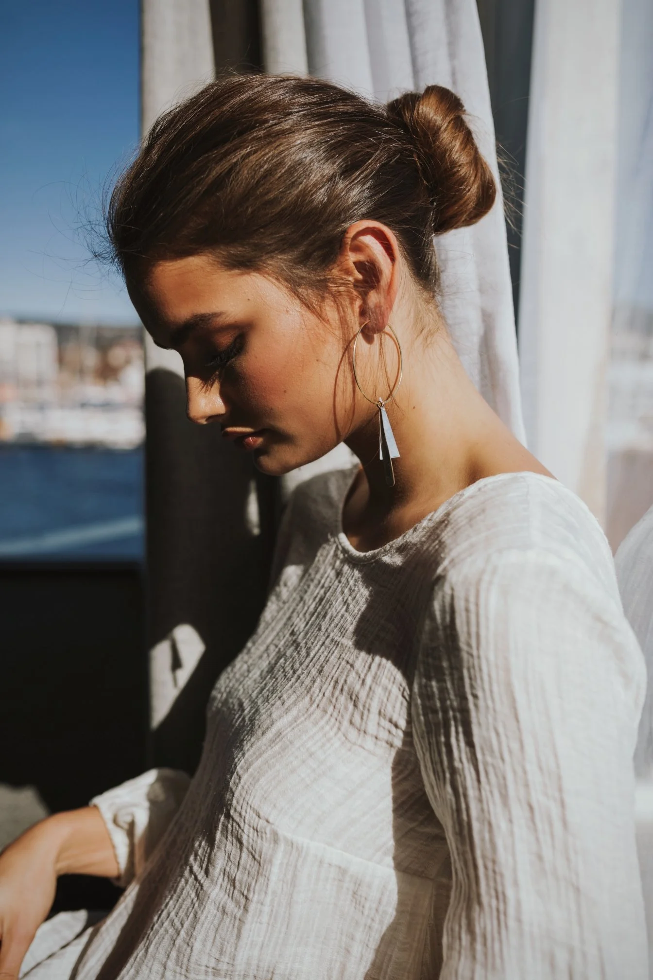 Model sits in sunlight in hotel room.