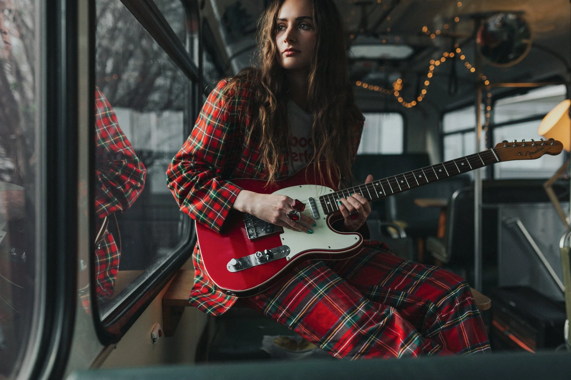 Guitarist sits in bus and looks out of window for personal branding photography.