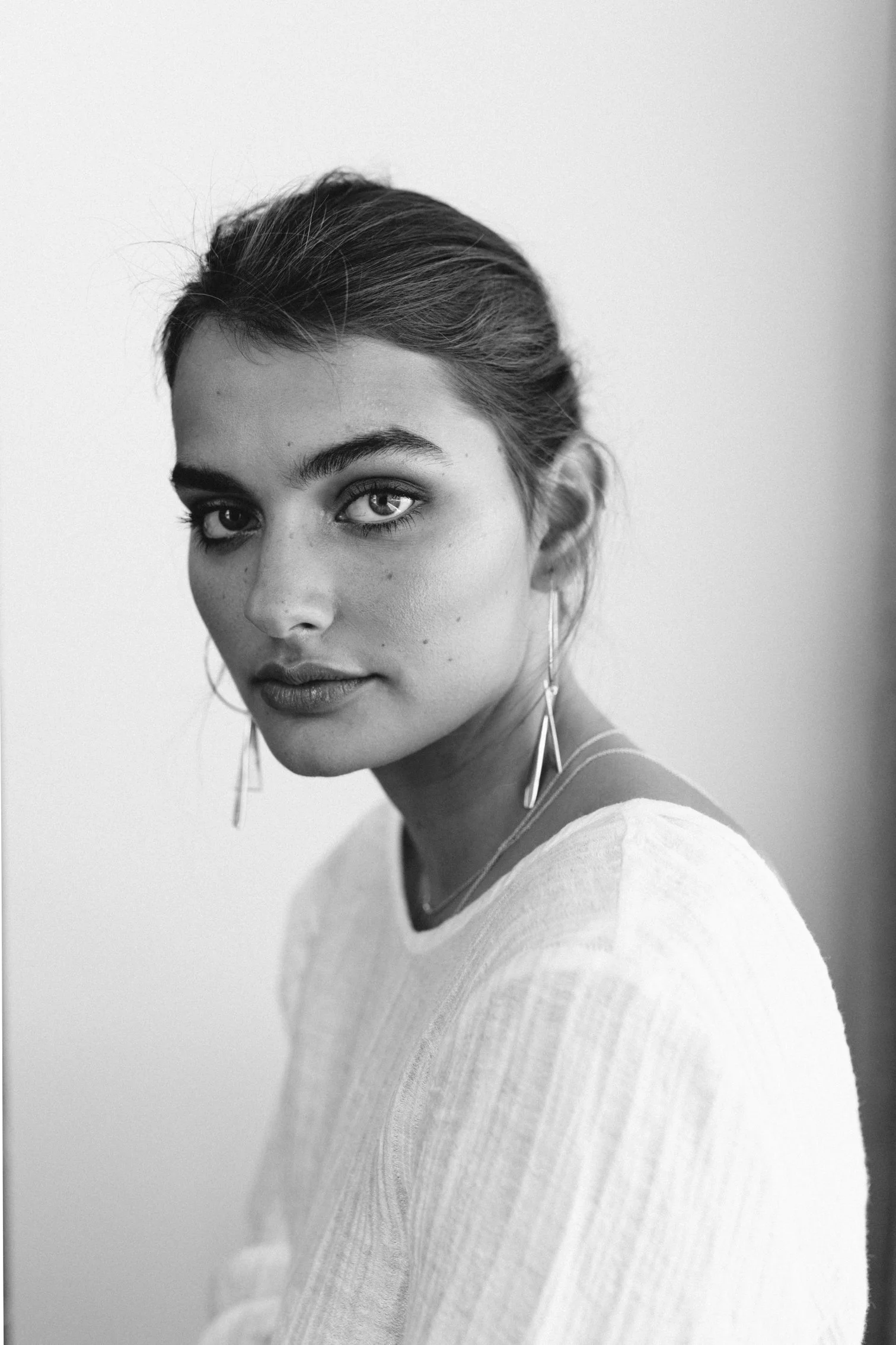 Model stares into camera wearing white top.
