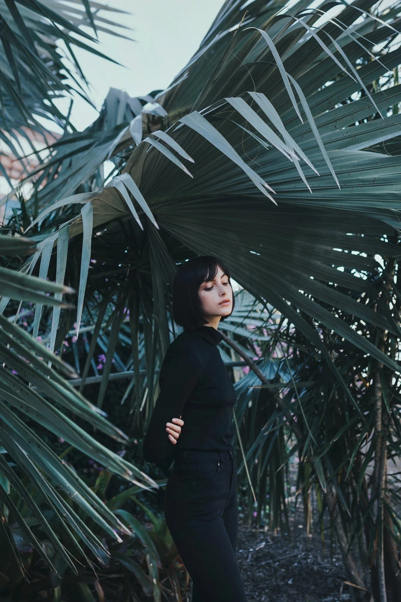 Model stands in tropical garden looking serene.
