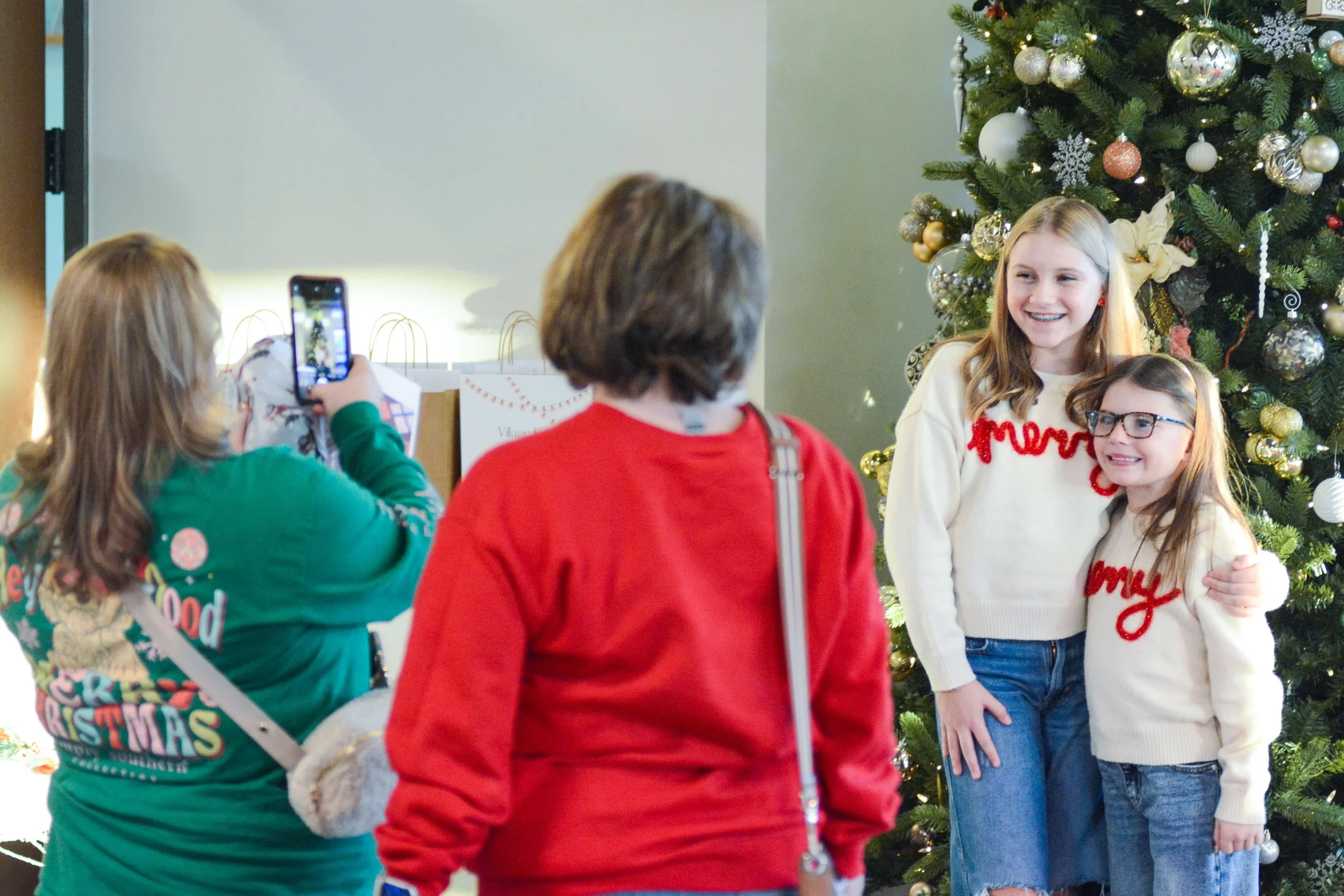 sisters taking photo in front of christmas tree