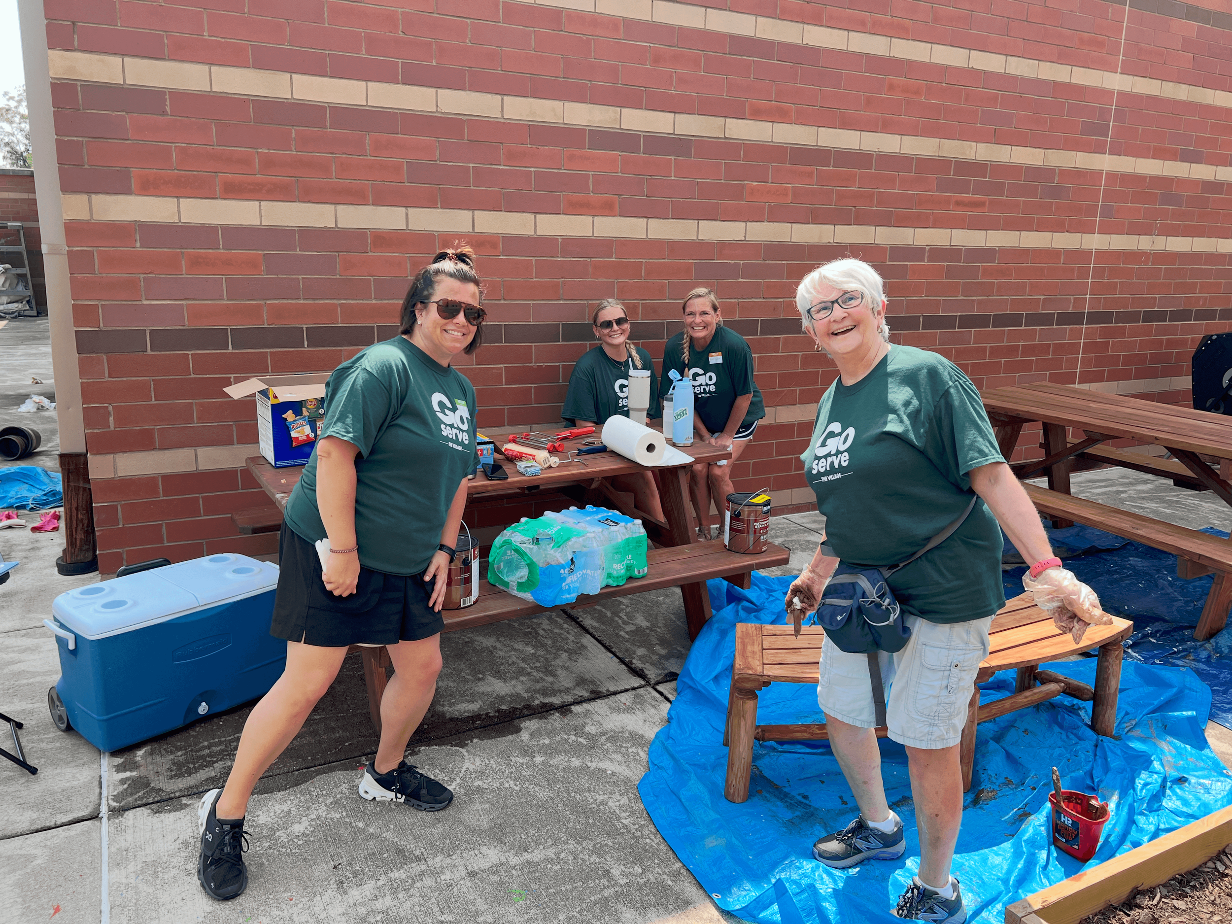 women staining outdoor benches