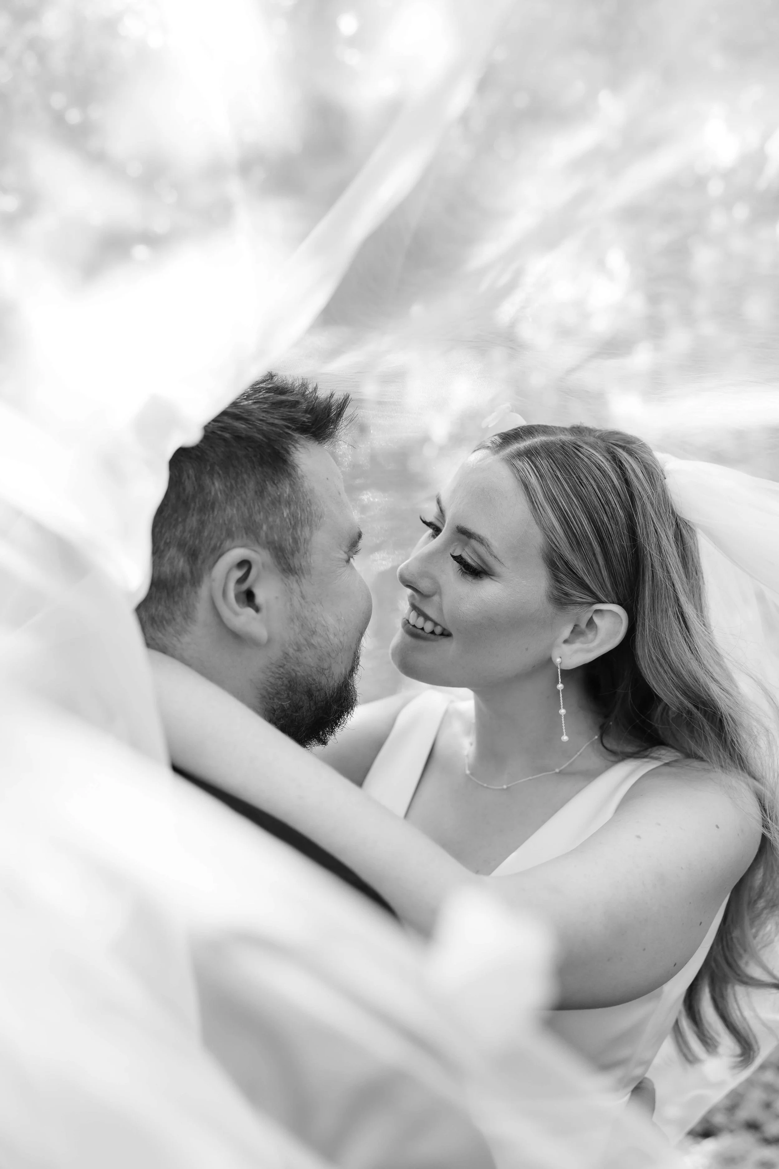 Editorial black and white wedding image of a near-kiss under a floating veil 
