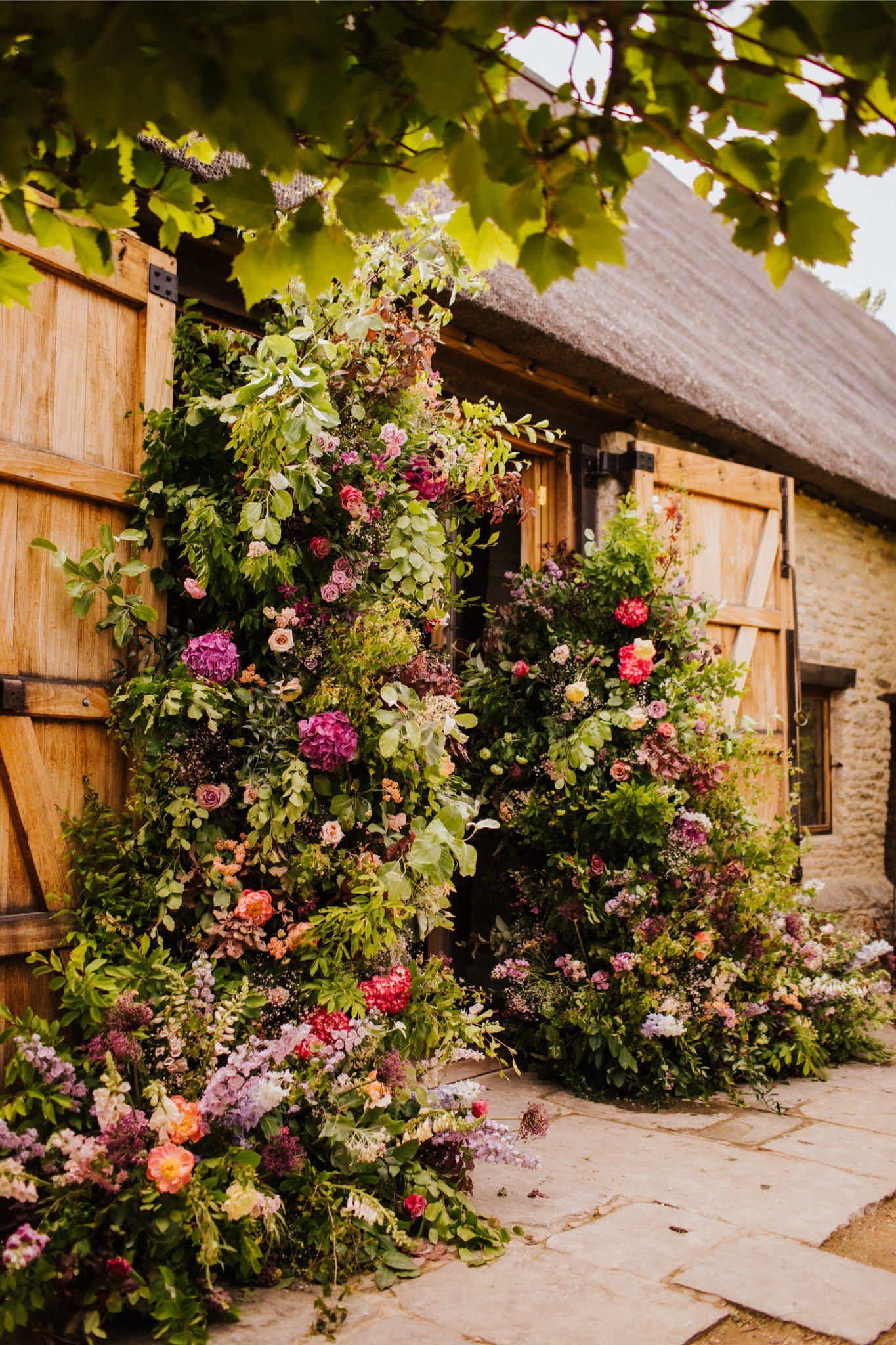 Colorful flower arrangements outside a rustic wooden door with open barn-style shutters.