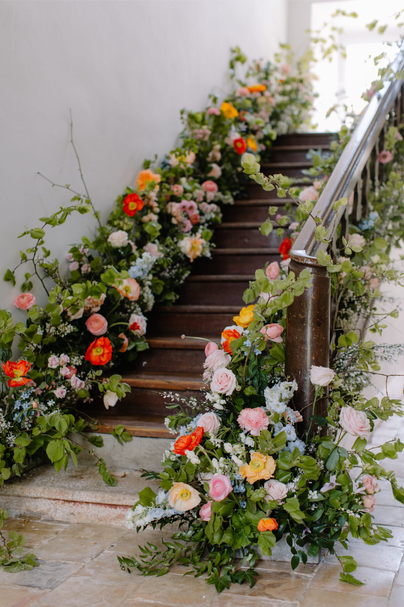 Decorated wooden staircase with colorful flowers and greenery along the sides and railing.