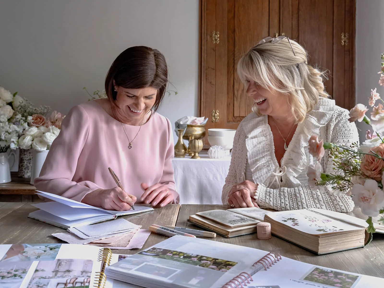 Wedding florists working in a studio planning flowers with books fresh flowers