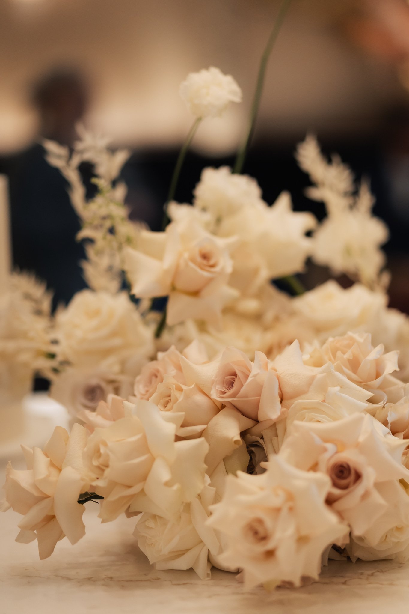 A bouquet of cream-colored roses and white flowers arranged on a table.