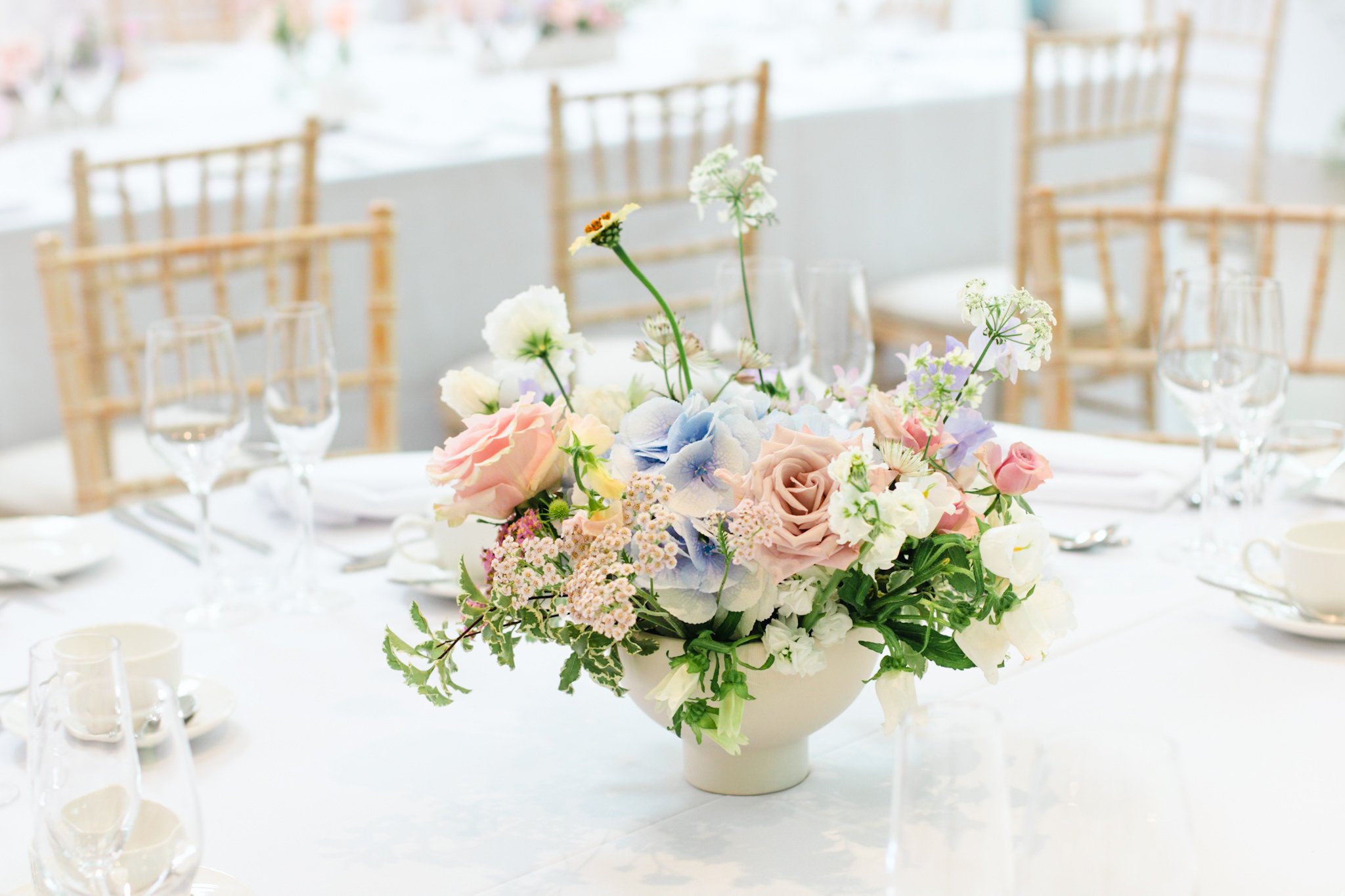 A floral arrangement with pastel-colored flowers on a dining table set for a formal event.