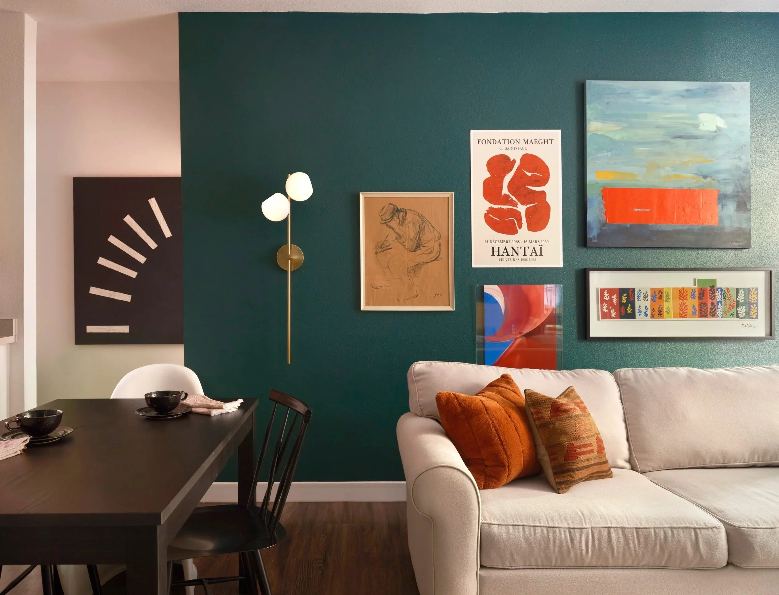 A gallery wall of large artworks matches the scale of this long living room wall.  Buying new pieces this large was out of our budget, so we found digital downloads, FBMP deals and painted two of the canvas ourselves!  