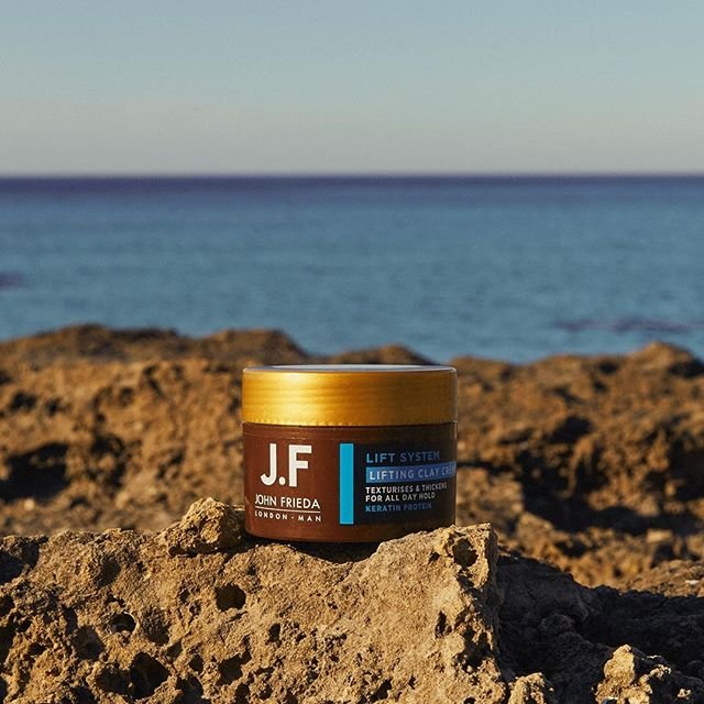 John Frieda Lift System Lifting Clay Cream on rocky shore with ocean background