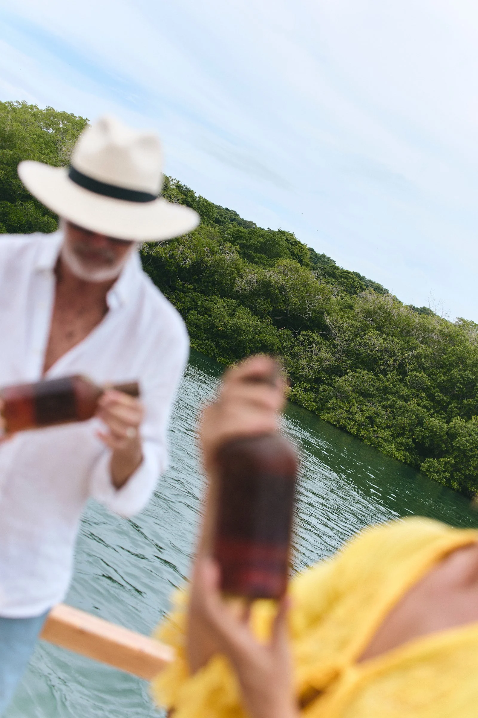 Guests hold bottles of sea-aged Colombian rum aboard a boat near Cartagena during The Drift, a WhereNext Original experience.