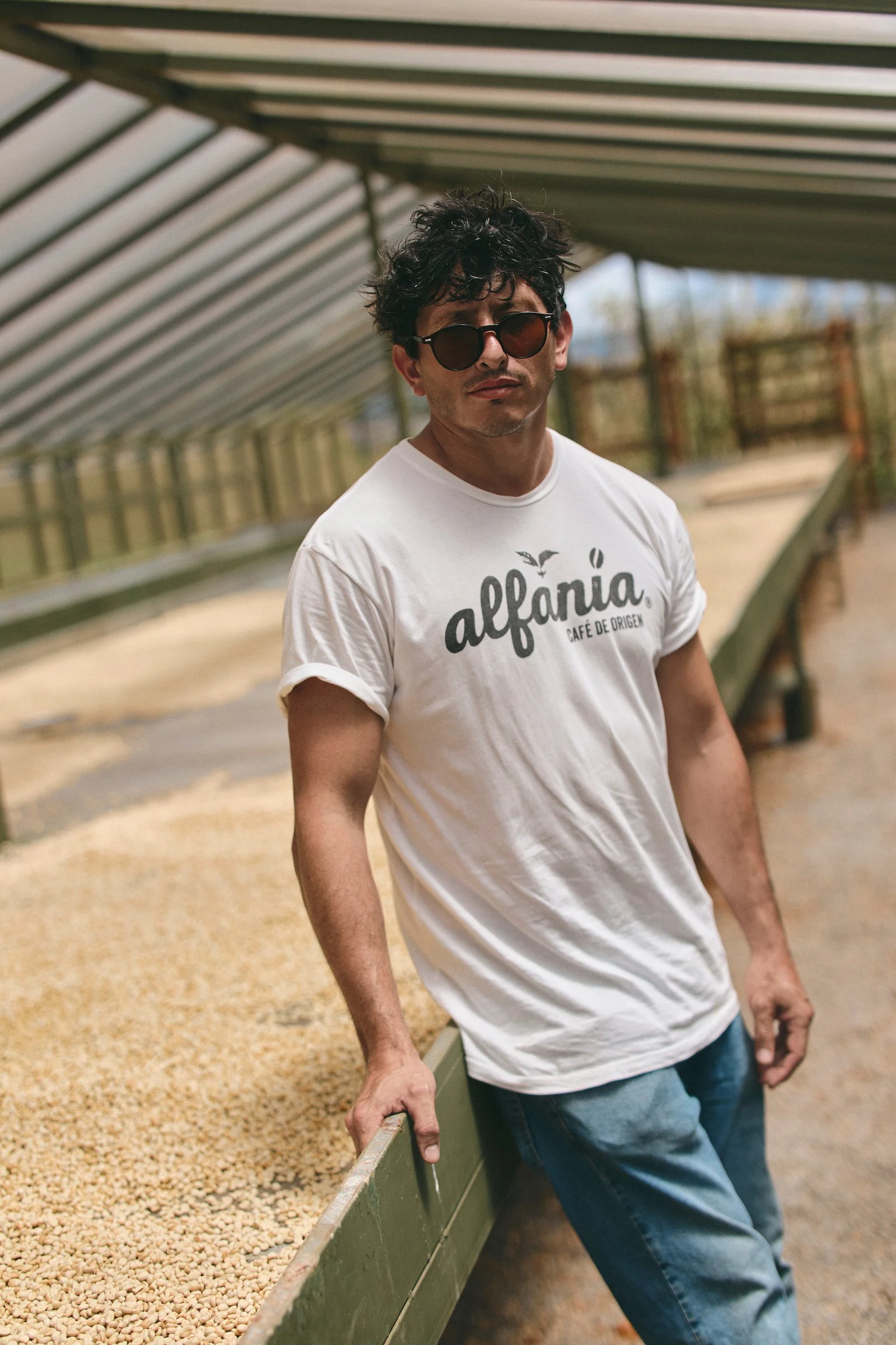 The owner’s grandson stands beside the drying beds at Alfania Coffee Farm wearing the finca’s café de origen T-shirt.