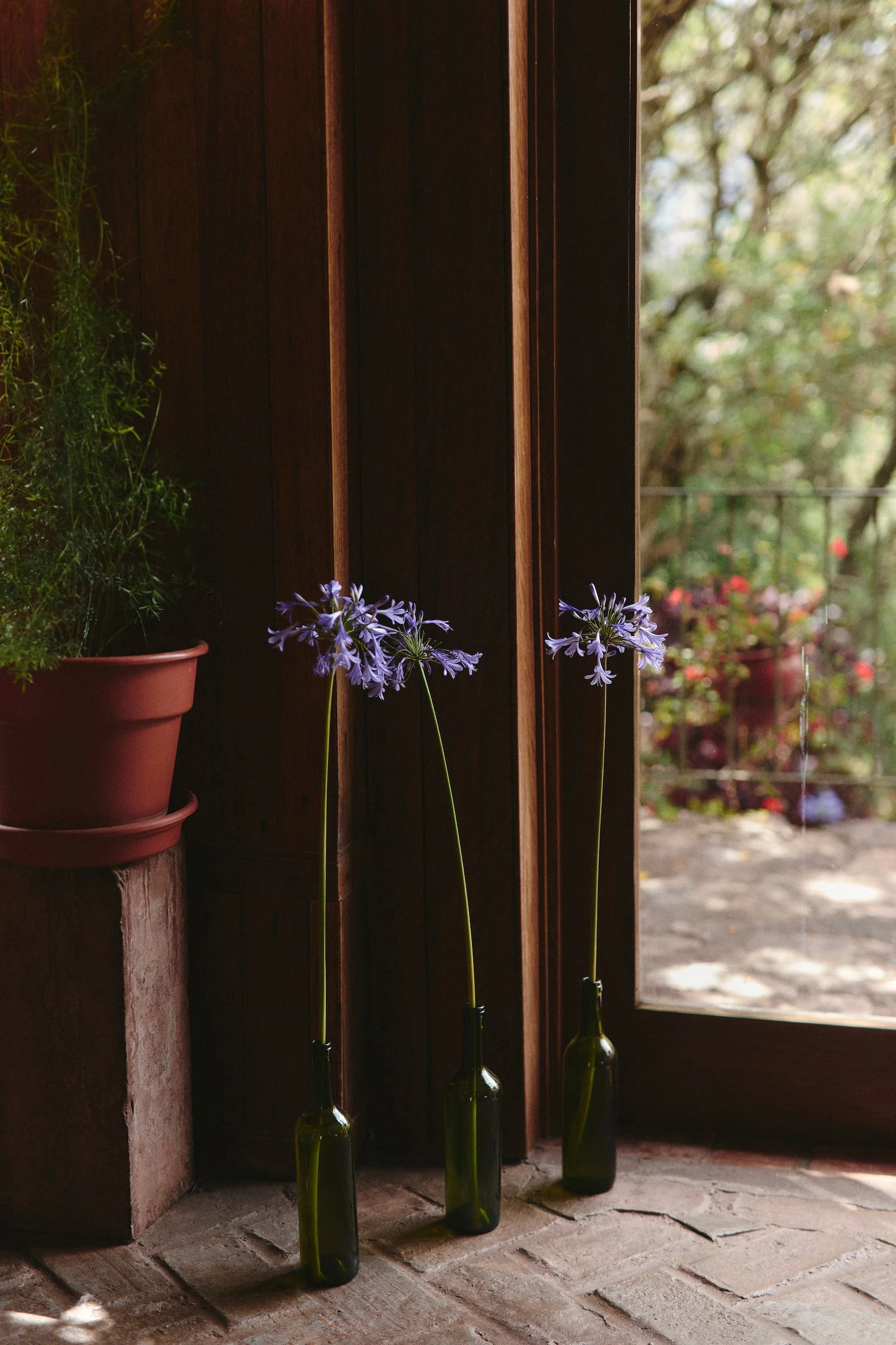 Flowers in glass bottles by a wooden doorway at Hacienda Huayoccari, a private Sacred Valley estate featured by luxury Peru DMC WhereNext Travel.