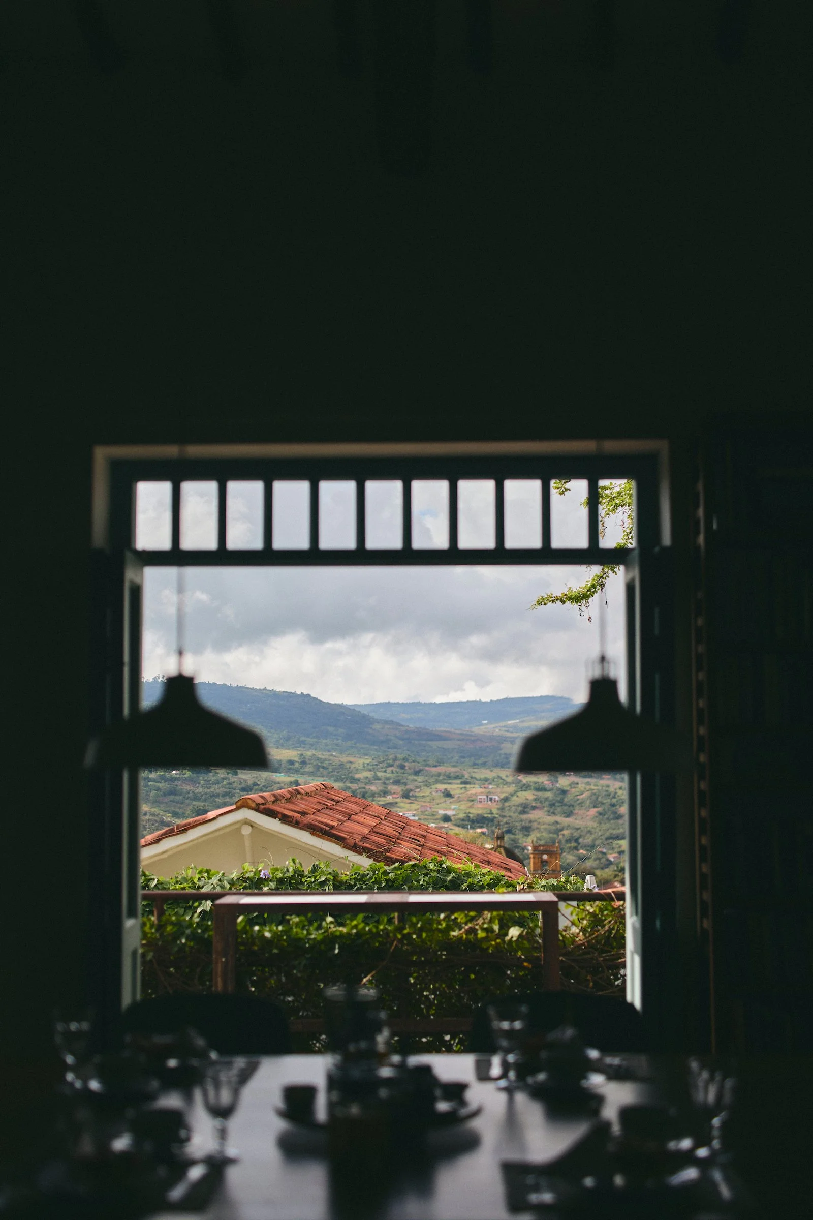 Casa Barichara’s shared dining area overlooking the red-tiled rooftops, green hills, and Andes surrounding Barichara, Colombia.