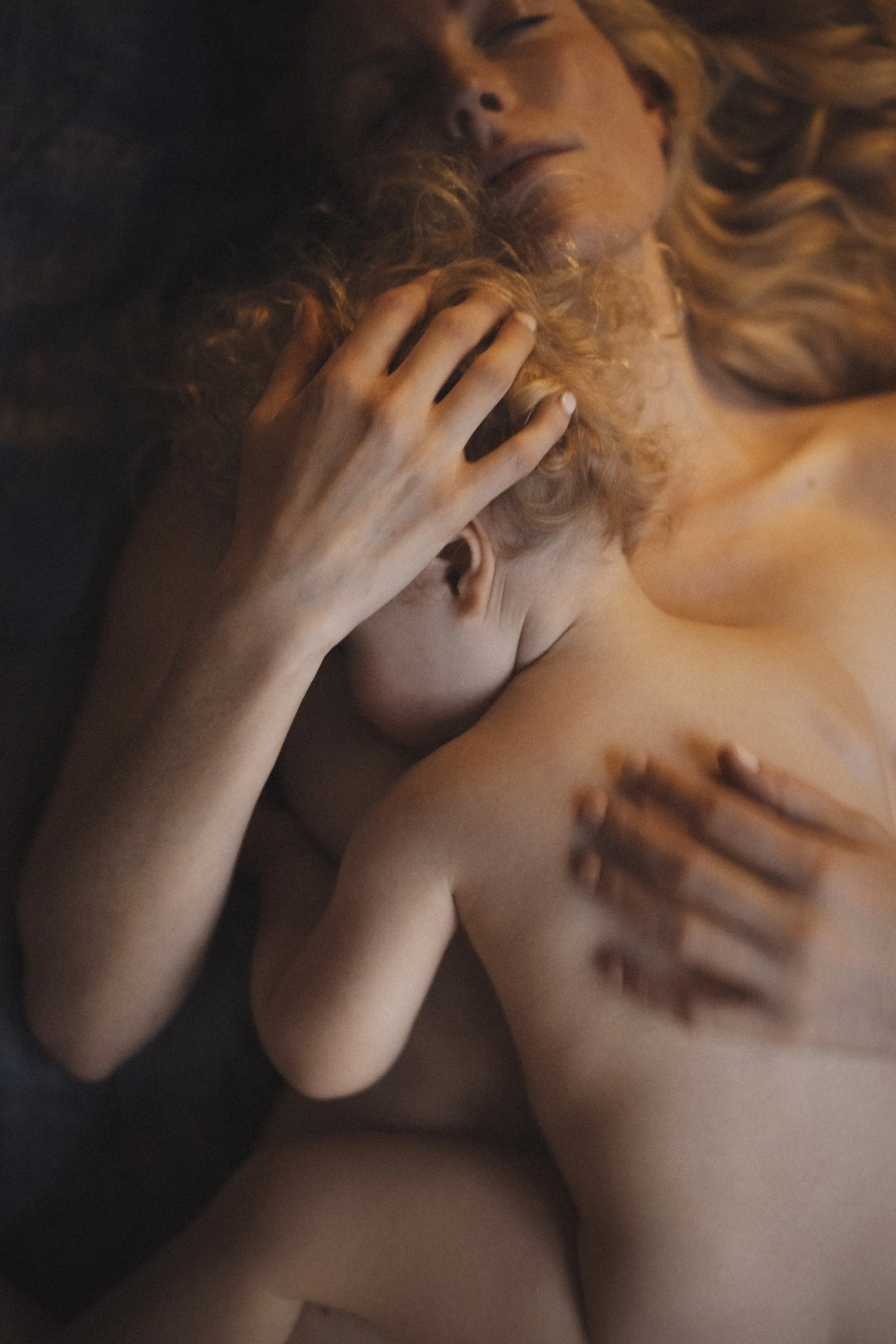 A woman and a child laying closely together, embracing and touching each other affectionately.