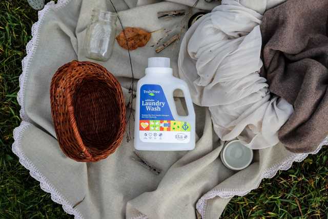 A jug of Truly Free Home Laundry Wash lying on a blanket