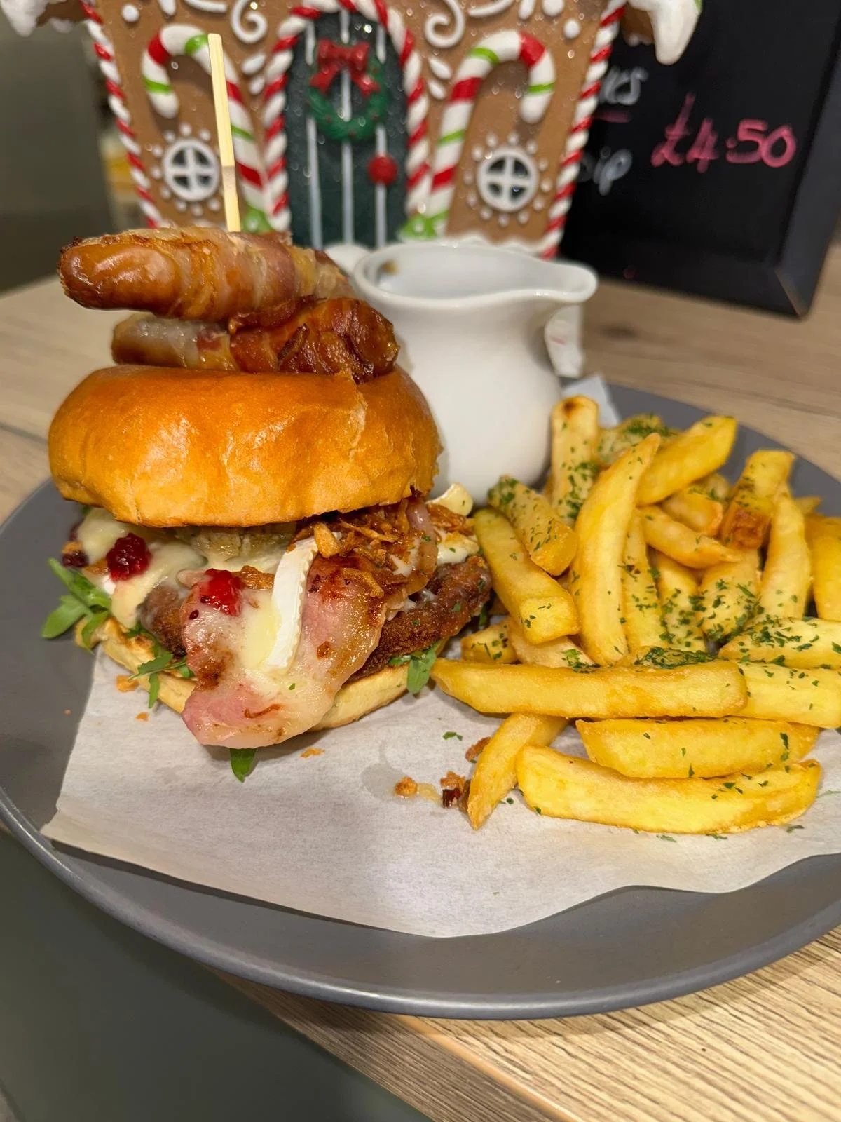 A burger with bacon, cheese, and toppings served with seasoned French fries on a plate.