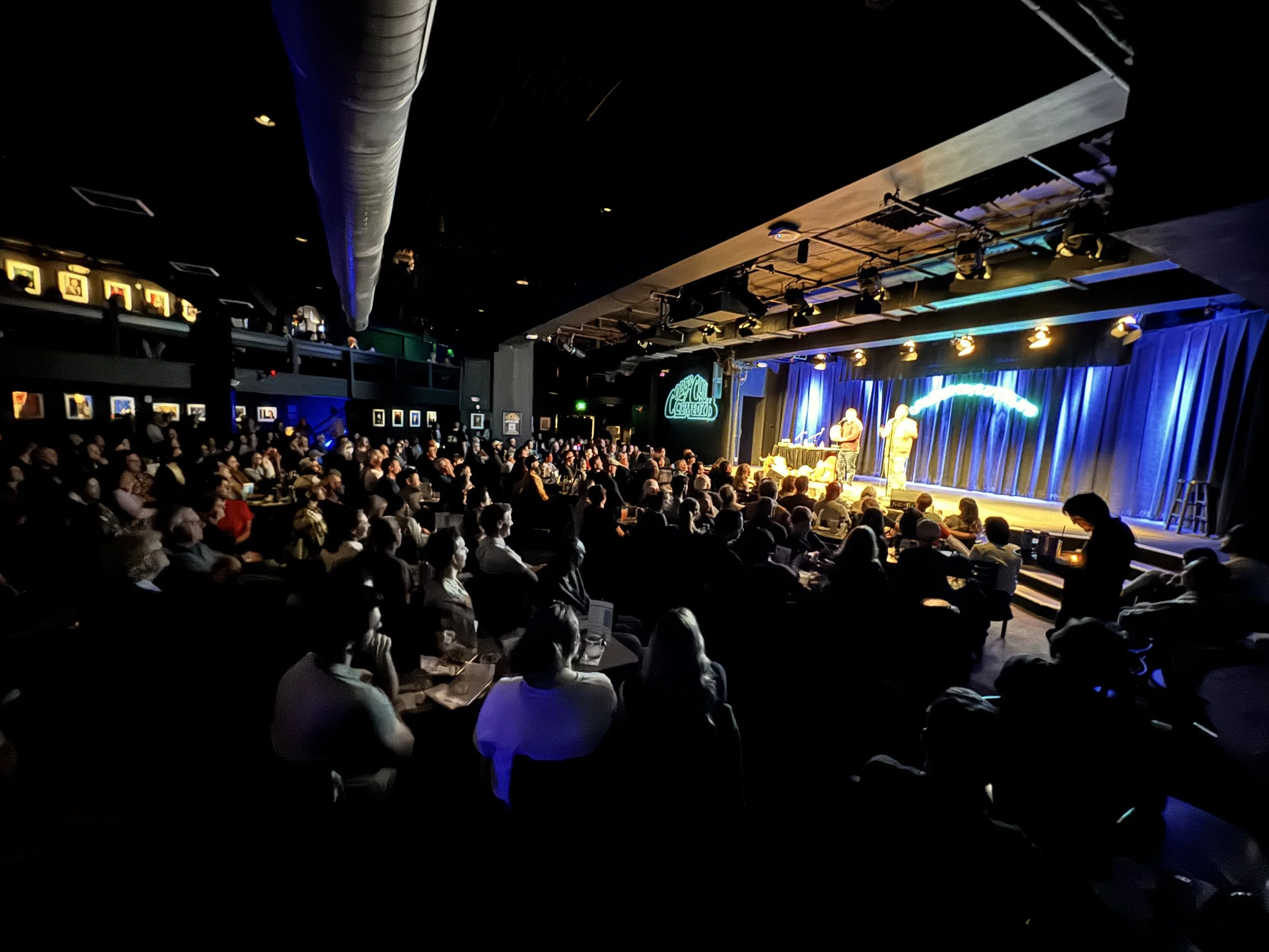 two men on stage at a sold out comedy club