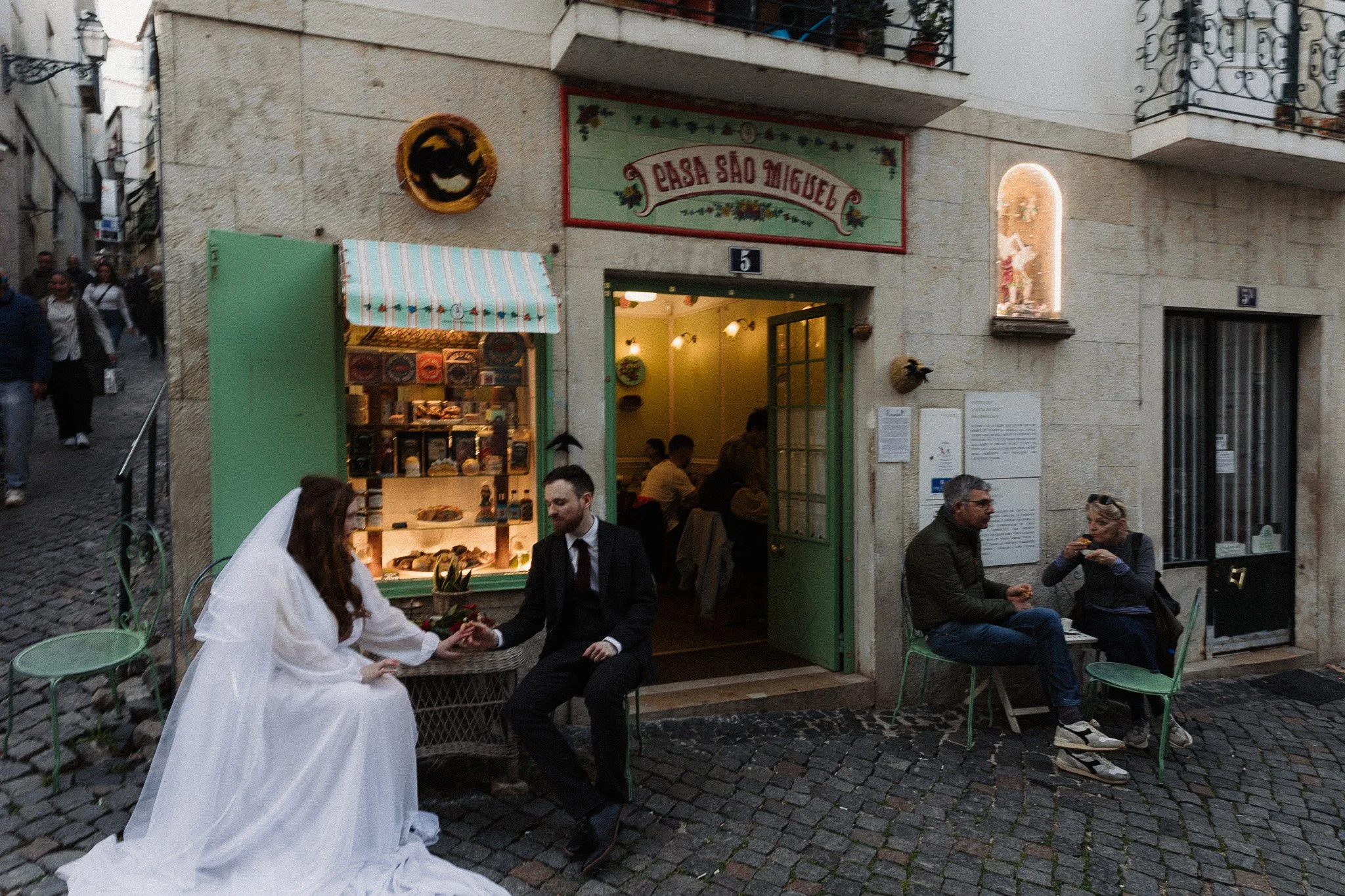 Couple holding hands outside a cafe in Lisbon Portugal celebrating their intimate elopement.