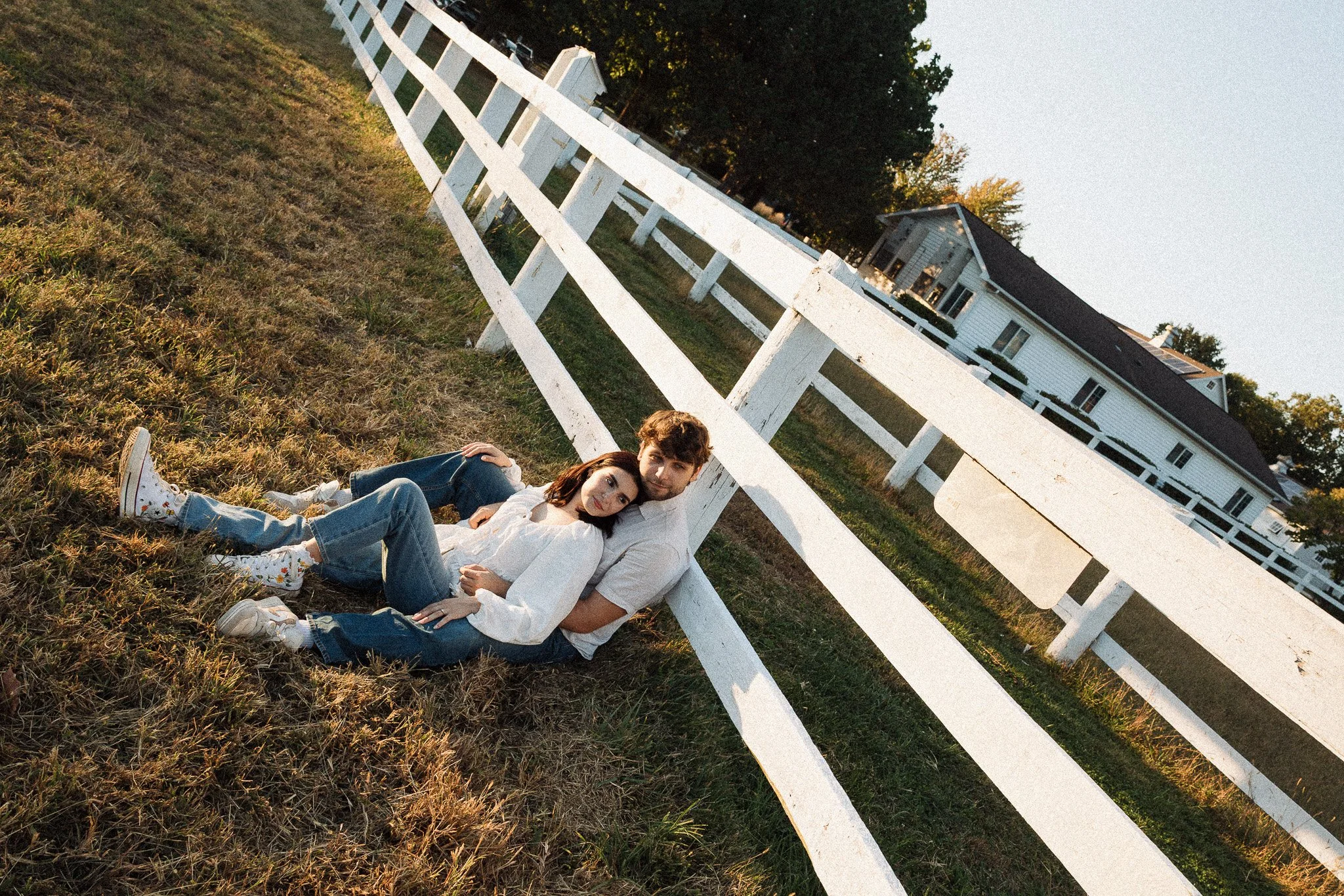 A young couple leaning against a fence at sunset on a small farm