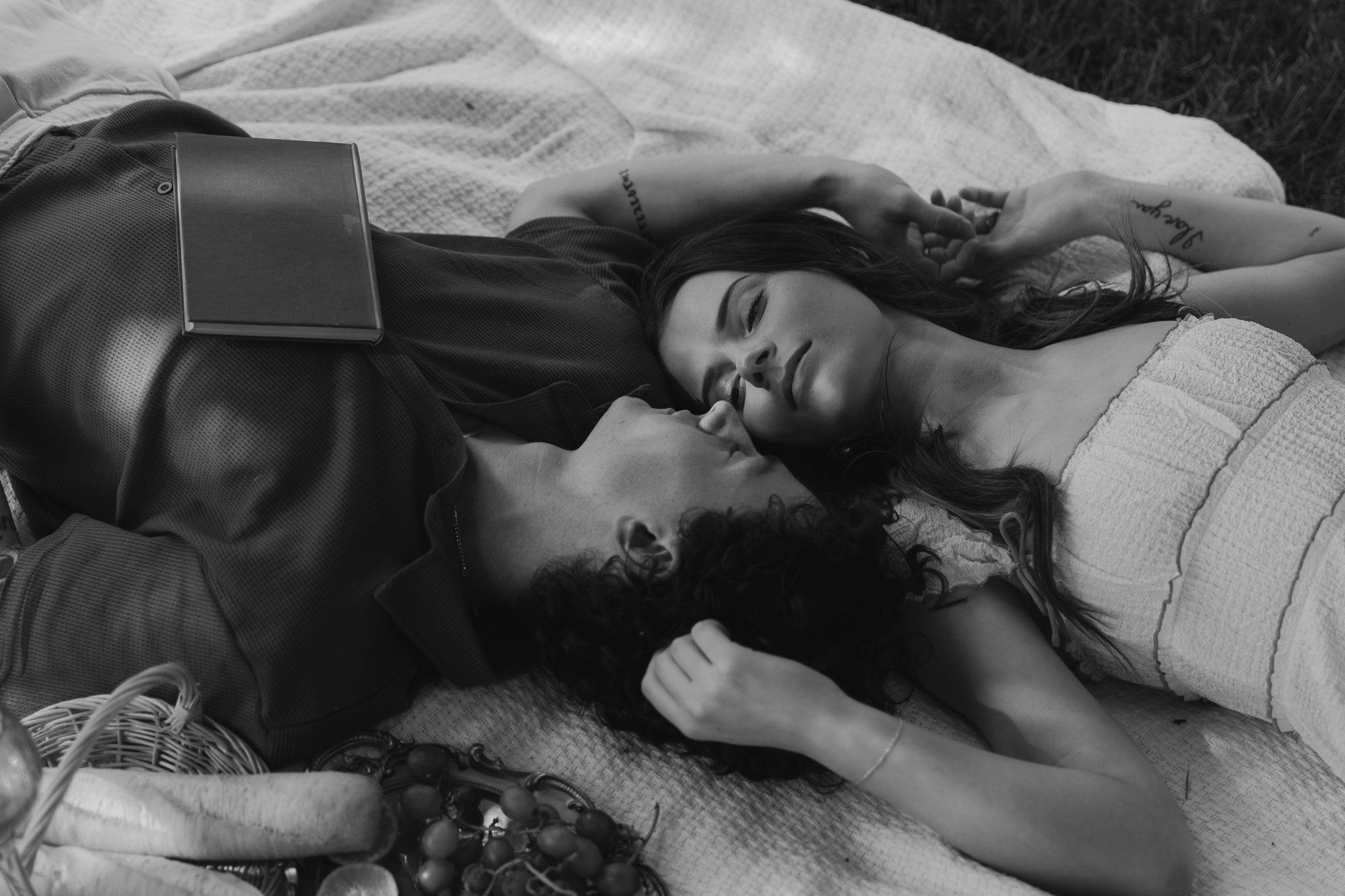 Black and white image of couple laying on a blanket closing their eyes