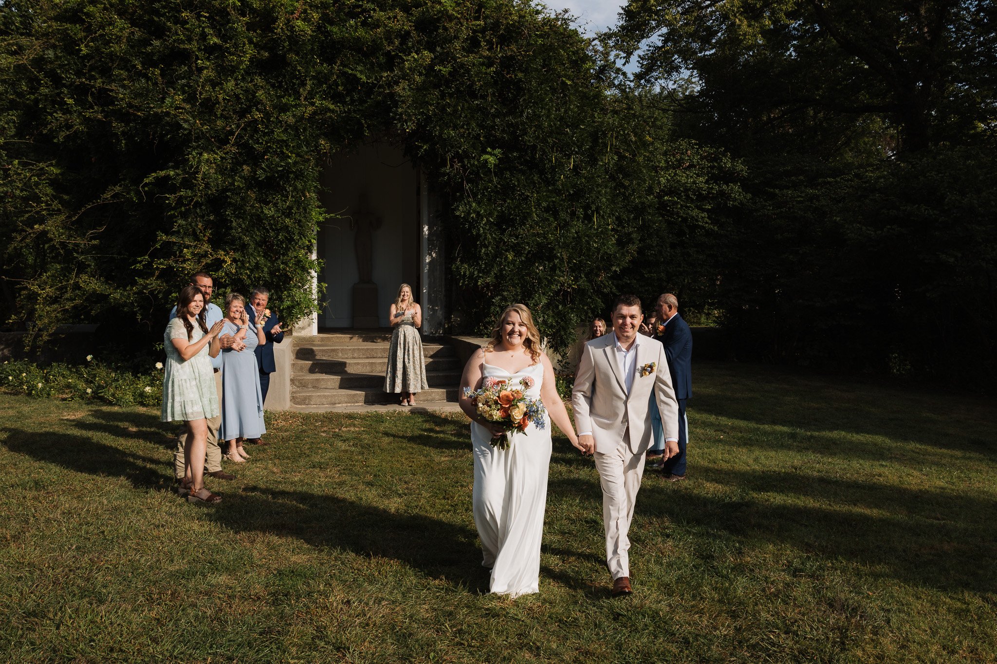 A couple eloping at their local park walk toward the camera with big smiles as they are announced husband and wife