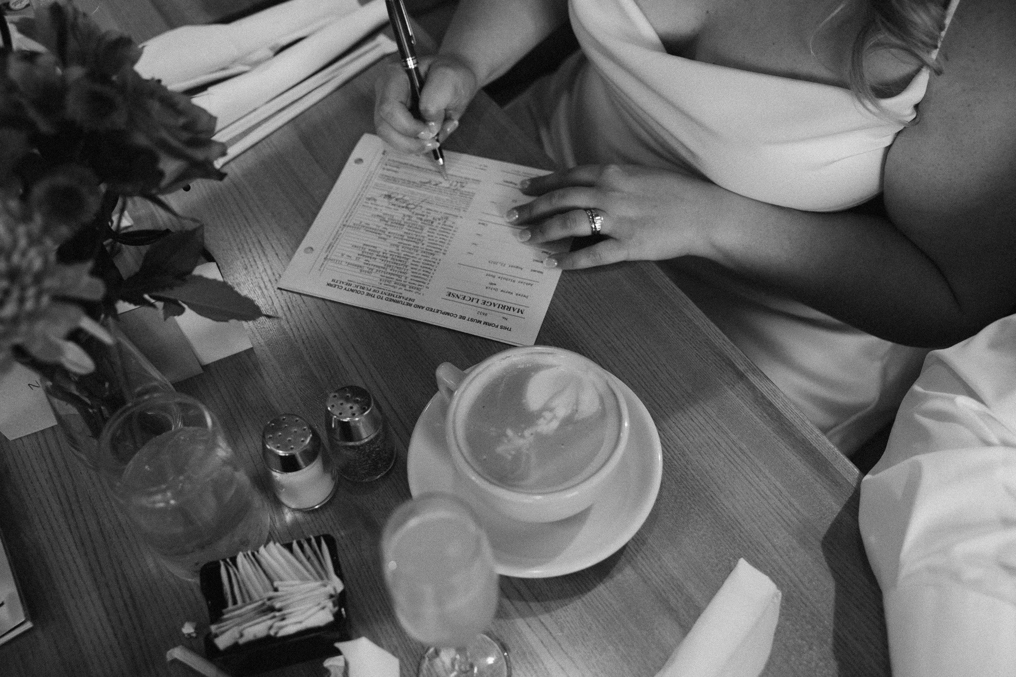 Bride who just eloped signs marriage license at their local restaurant in front of family