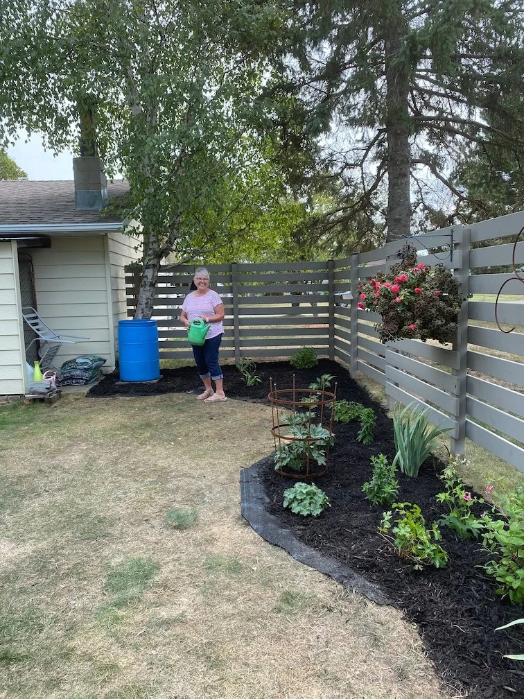 Homeowner enjoying landscaped garden along a fence near Ely, MN.