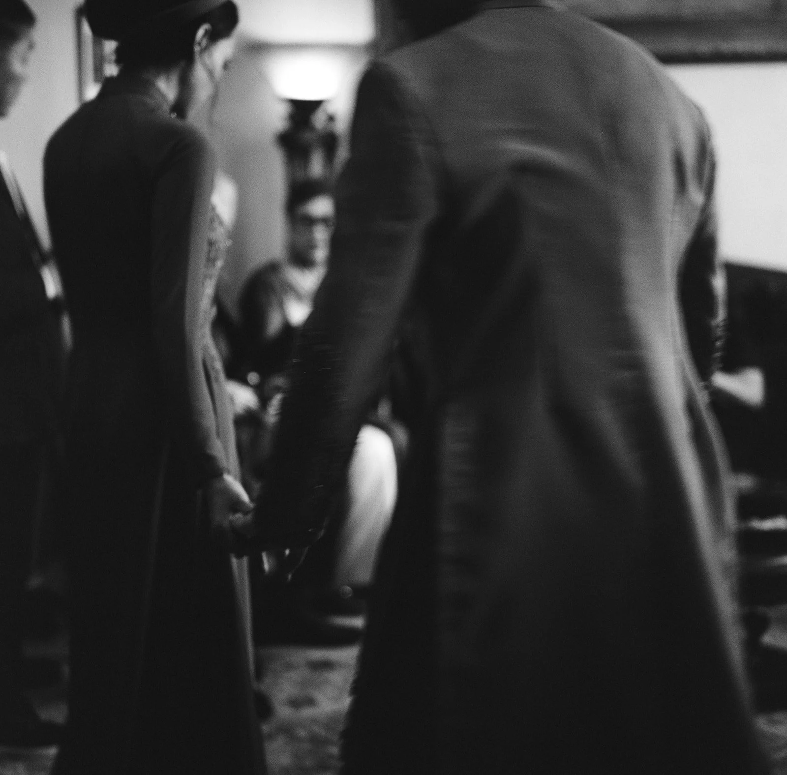 People holding hands in a black and white photograph, standing in a circle.