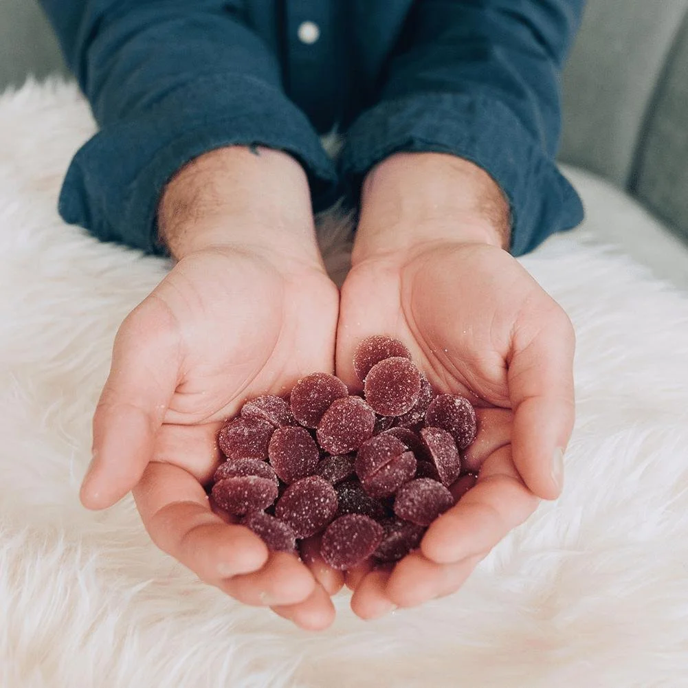 Hands holding a pile of purple Sunset Lake Cannabis medical marijuana gummies.