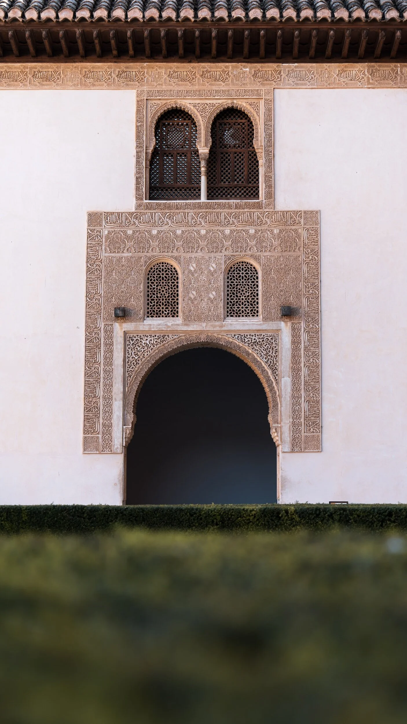 Architectural detail of a building with intricate carvings and lattice windows, featuring a large archway and decorative moldings.