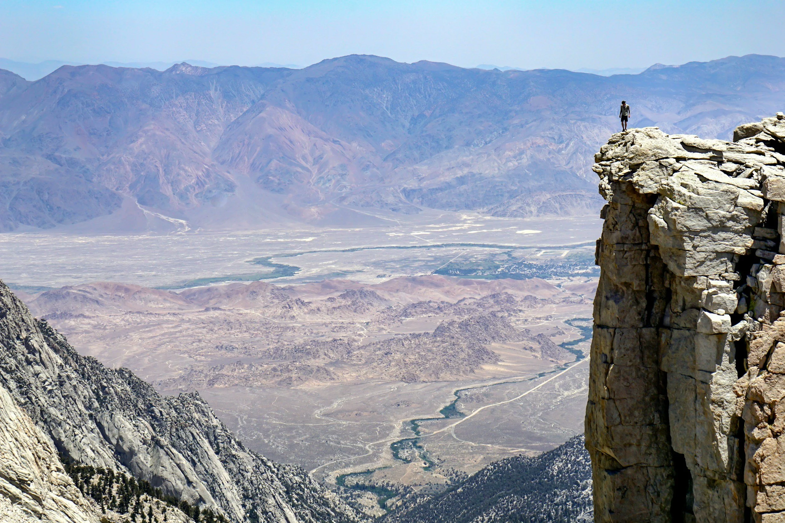 The Bitter Bitch Lifestyle Blog: Everyone Wants to Live YOLO.  A photo from the top of a mountain showing a sharp peak to the right and a lone climber standing atop near the edge.