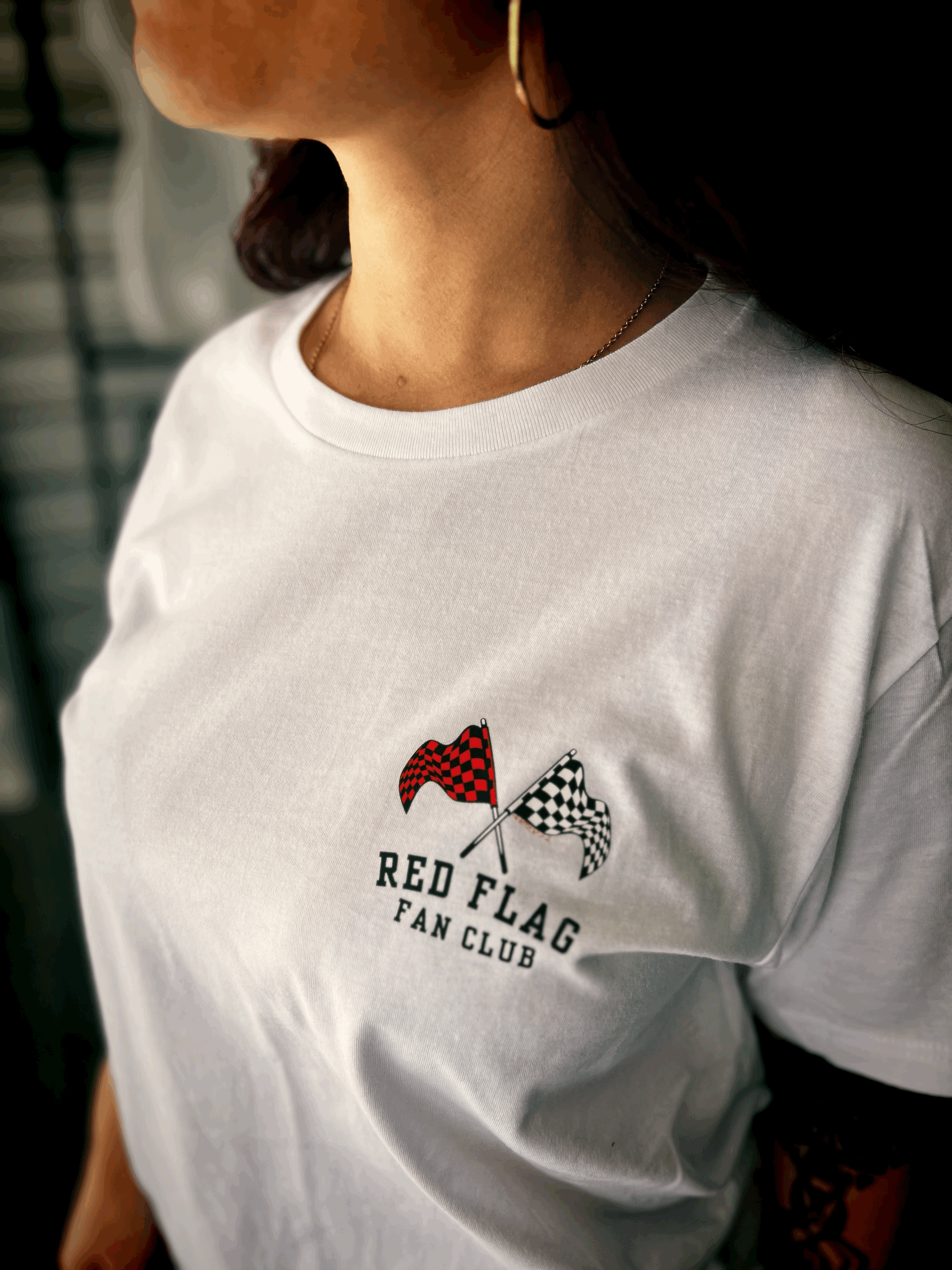 "Red Flag Fan Club" relaxed unisex tee in white with red and white checkered flag logo on back by The Bitter Bitch Co.