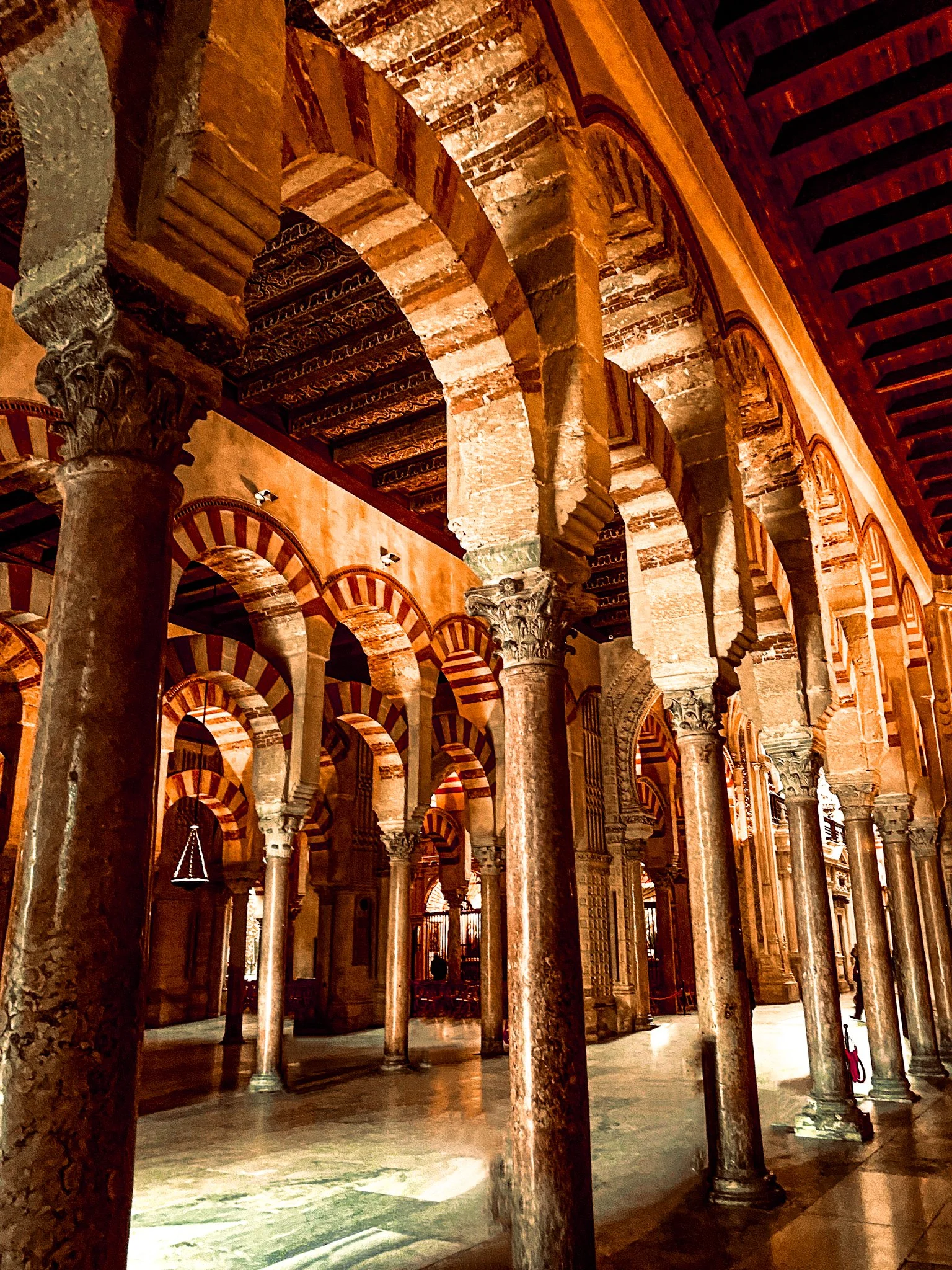 Interior of the Great Mosque of Córdoba featuring columns, horseshoe arches, and intricate architectural details.