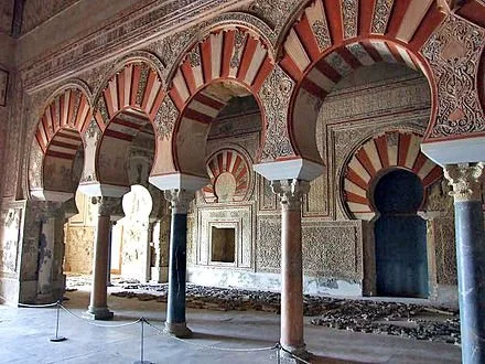 Interior of a historic building with ornate arches and columns, featuring intricate designs and patterns.
