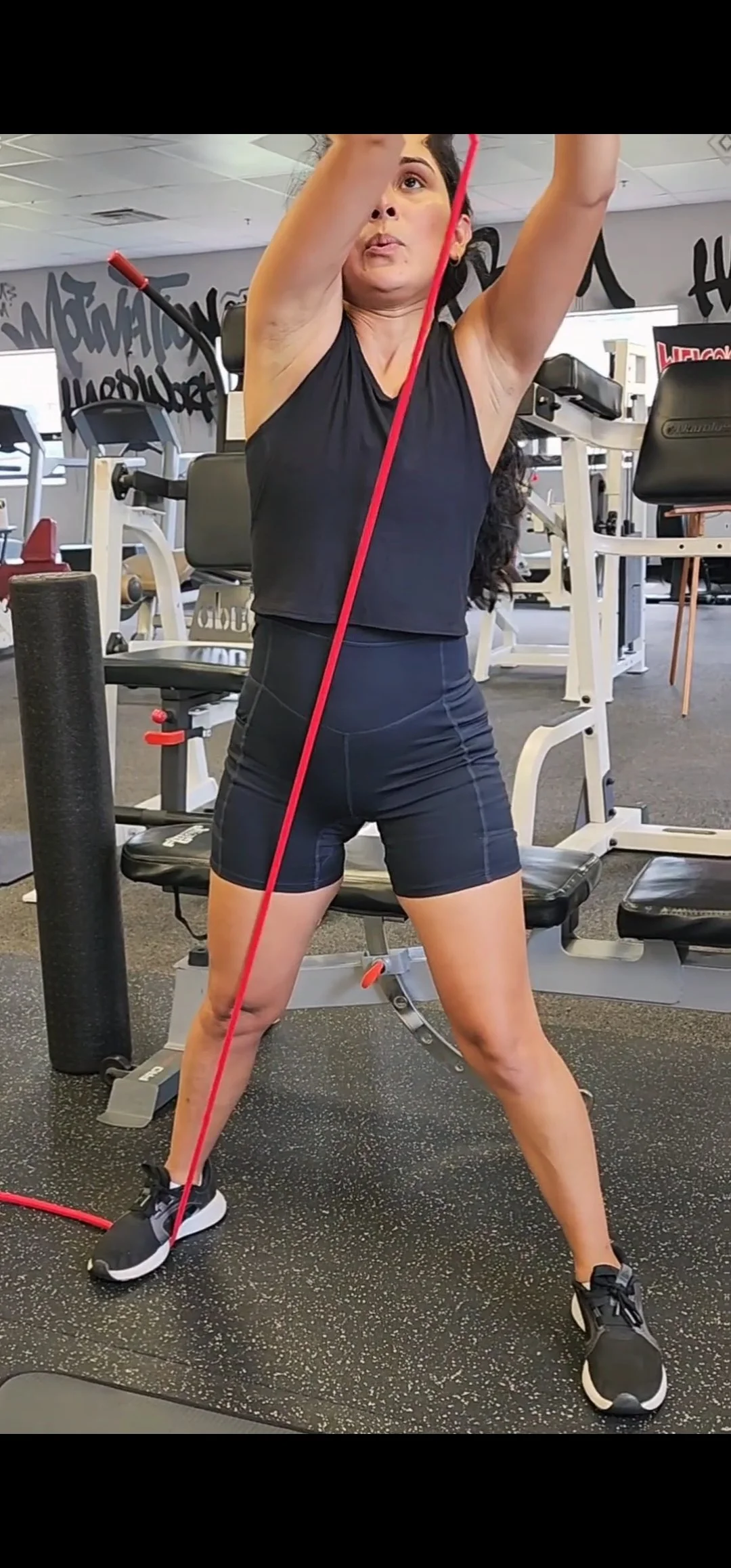 Woman in black athletic outfit using resistance band in gym.