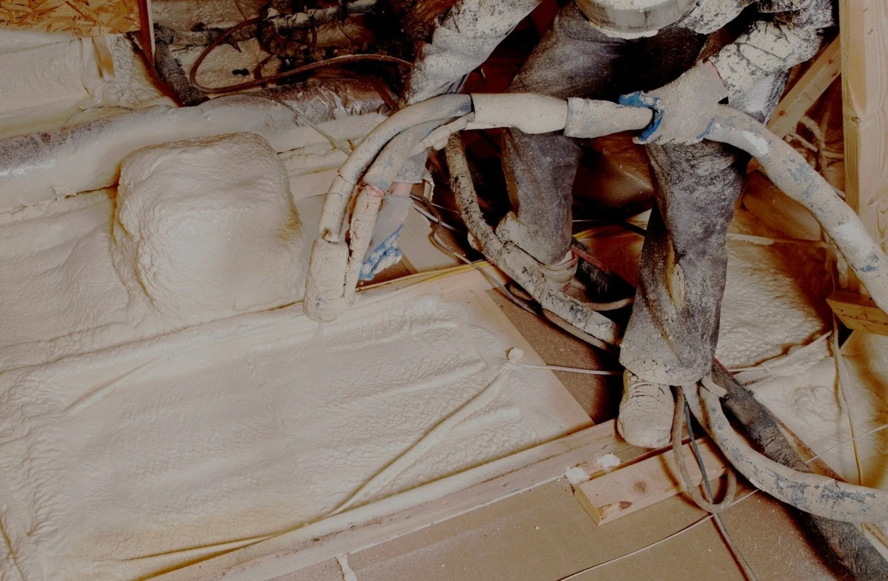 Insulation foam sprayed on walls and pipes in building interior under construction.