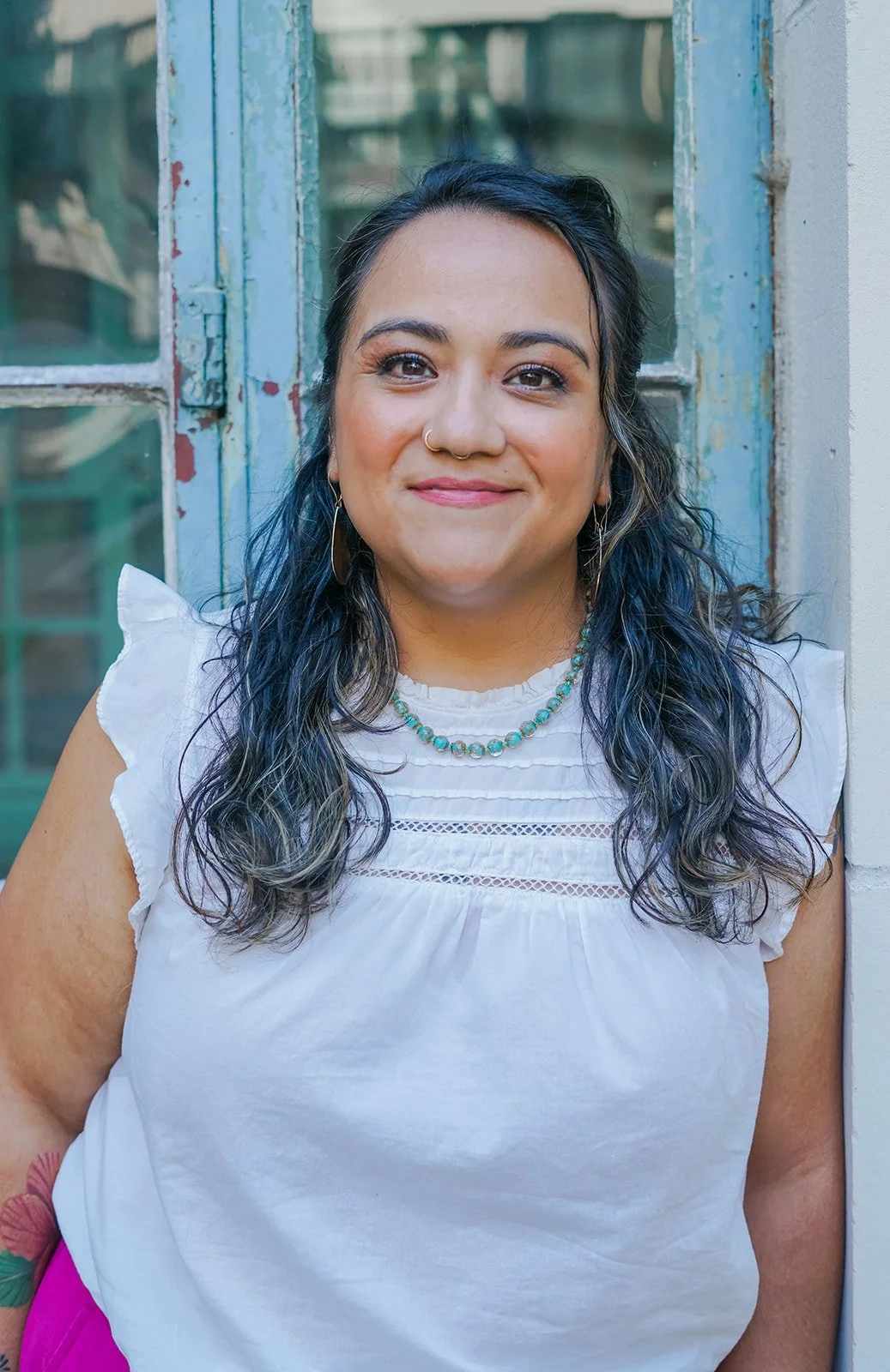 Professional headshot of a therapist standing outdoors in front of a light-colored doorway