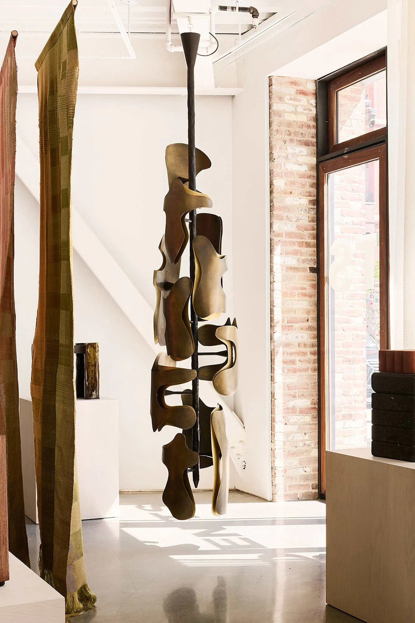 Okia pendant in gallery space with natural light and textile dividers