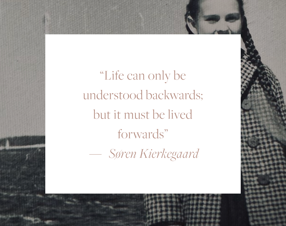 Quote card reading: "Life can only be understood backwards; but it must be lived forwards." — Søren Kierkegaard, overlaid on a vintage black and white photograph of Elina's mother as a young girl standing by the seaside.