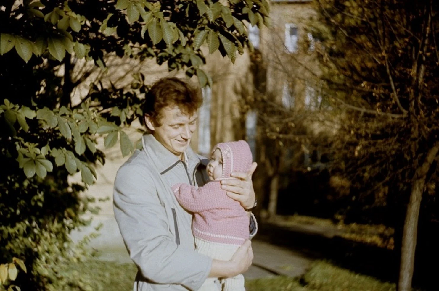 Baby Elina being held by her father during a sunny autumn walk.